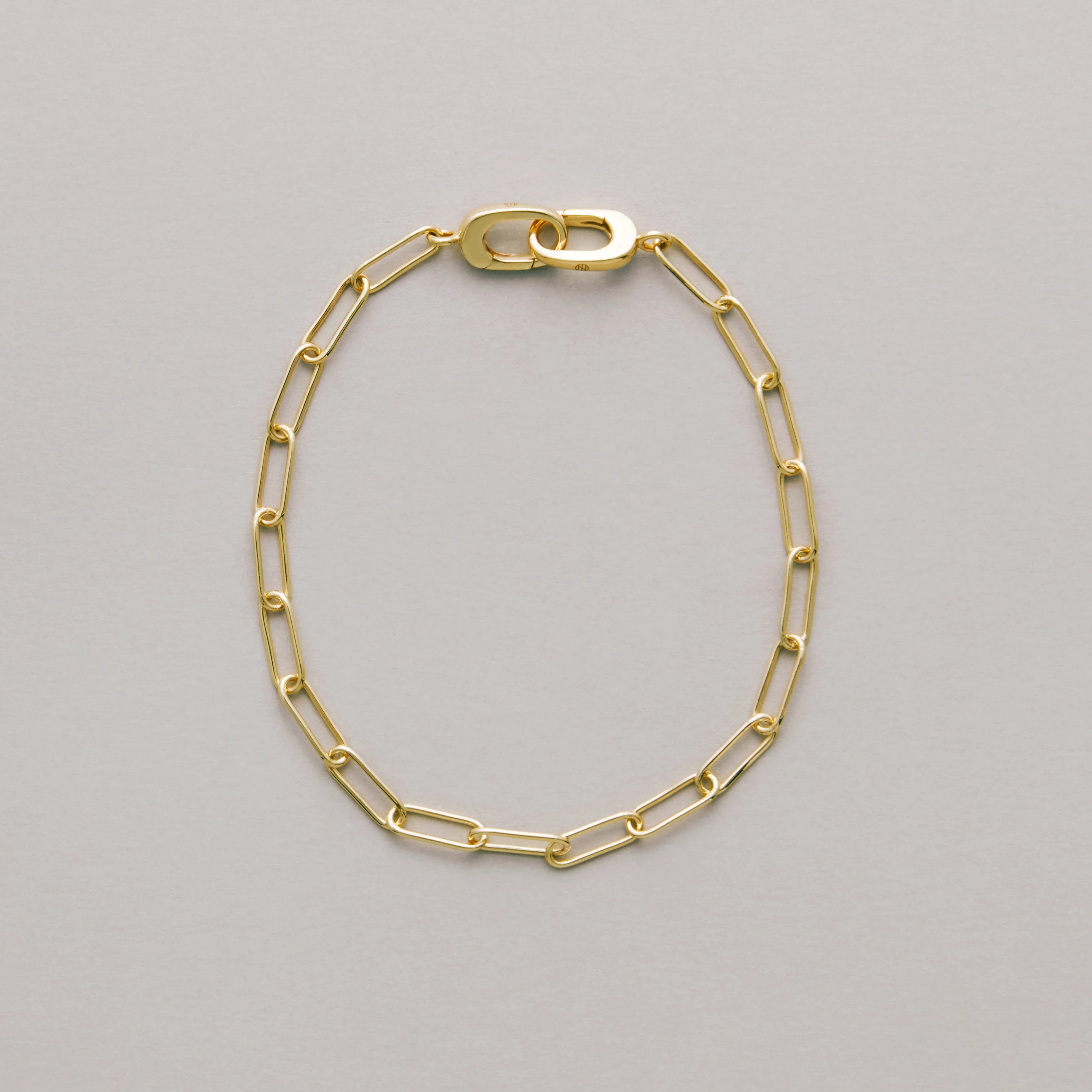 Gold paperclip chain bracelet on a light gray background