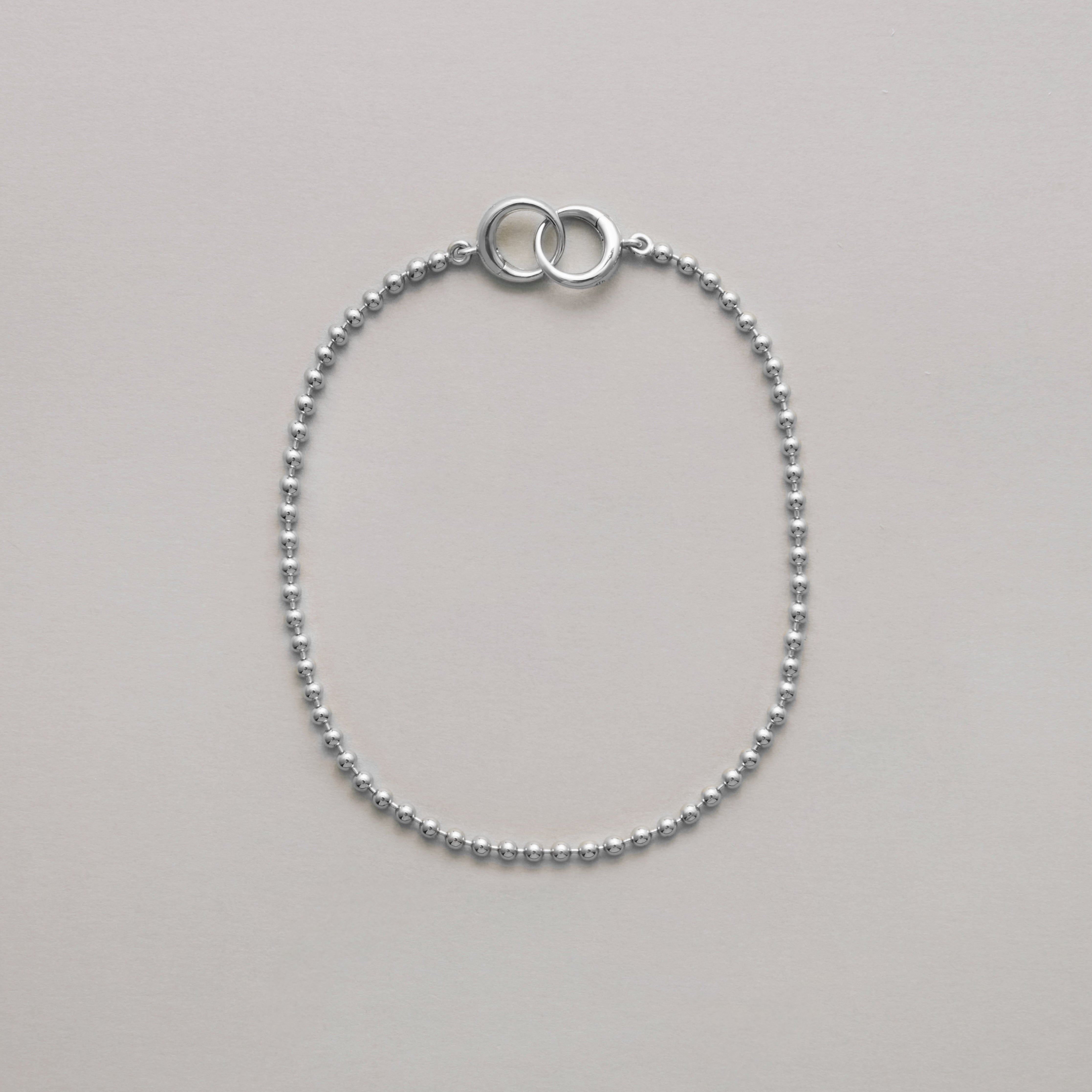 Silver beaded bracelet with interlocking loops on neutral background
