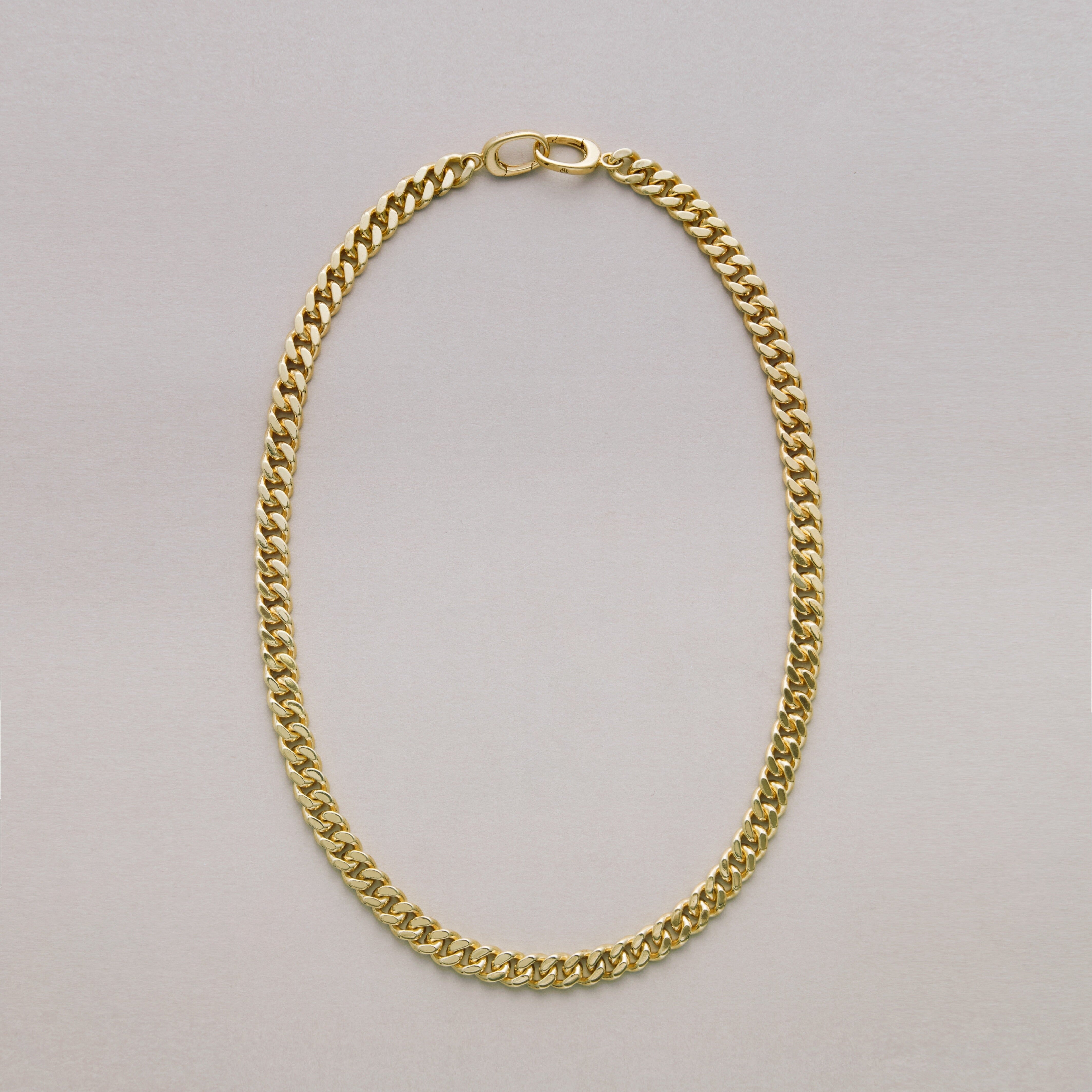 Gold Cuban chain necklace on a light gray background