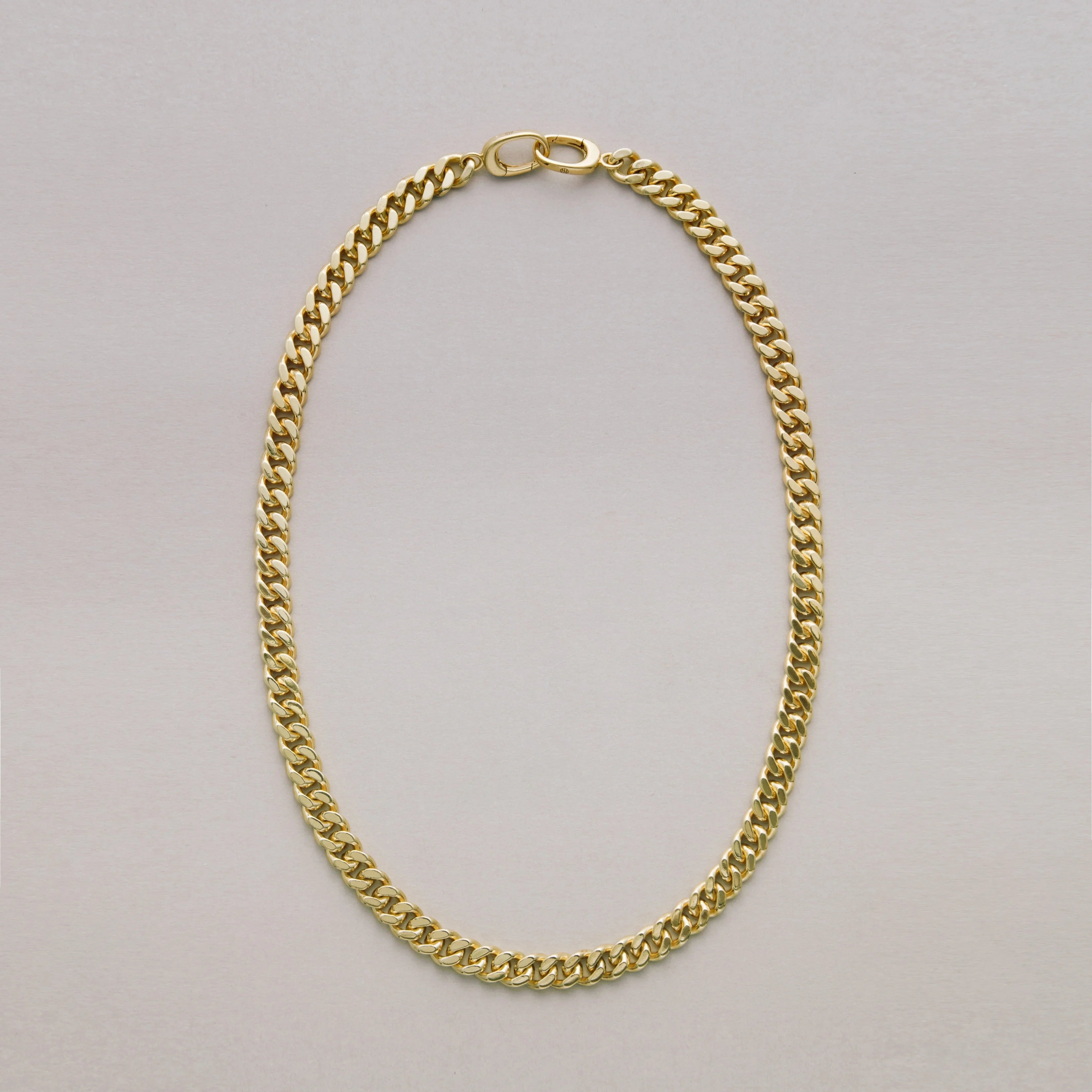 Gold Cuban chain necklace on a light gray background
