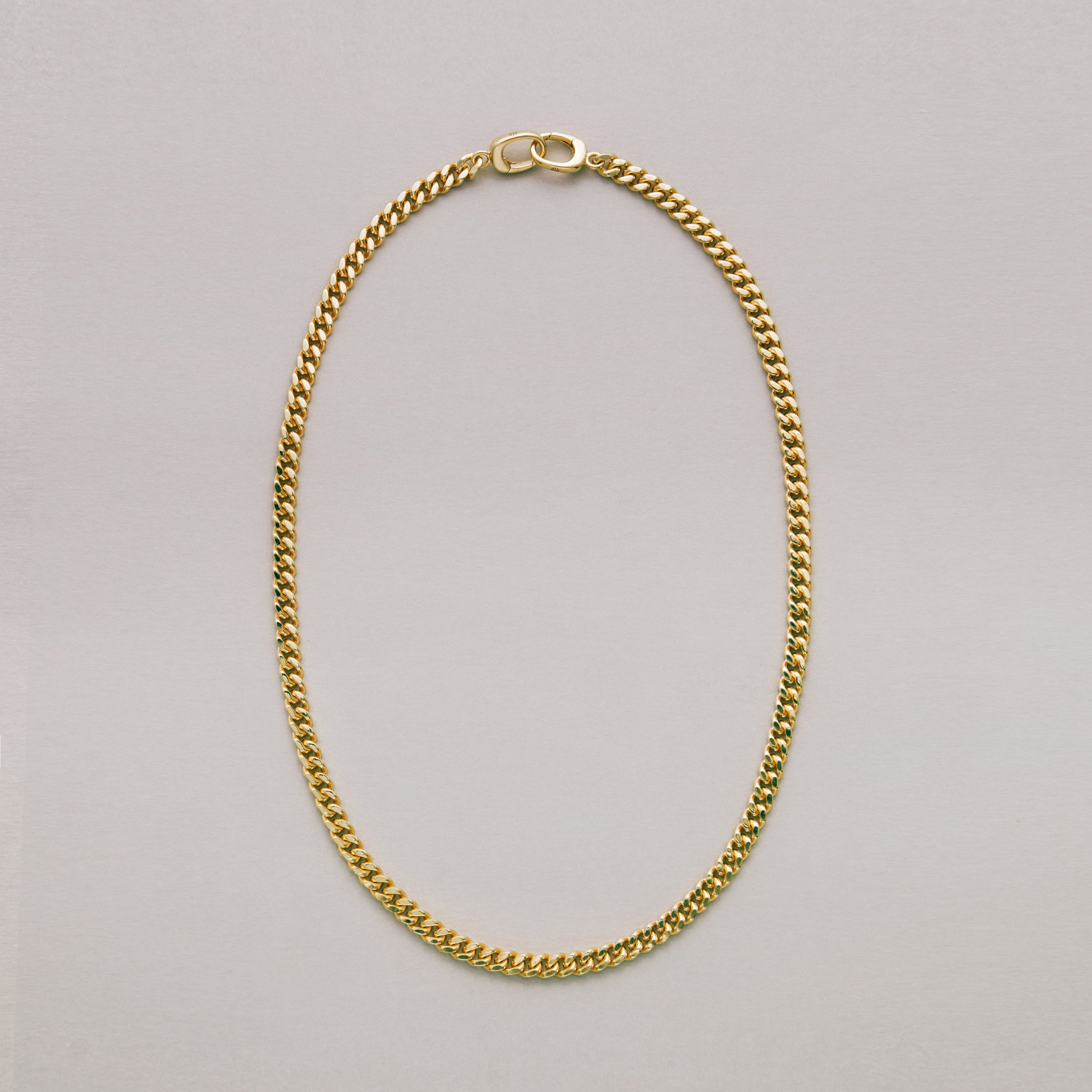 Sleek gold Cuban chain necklace on a light gray background
