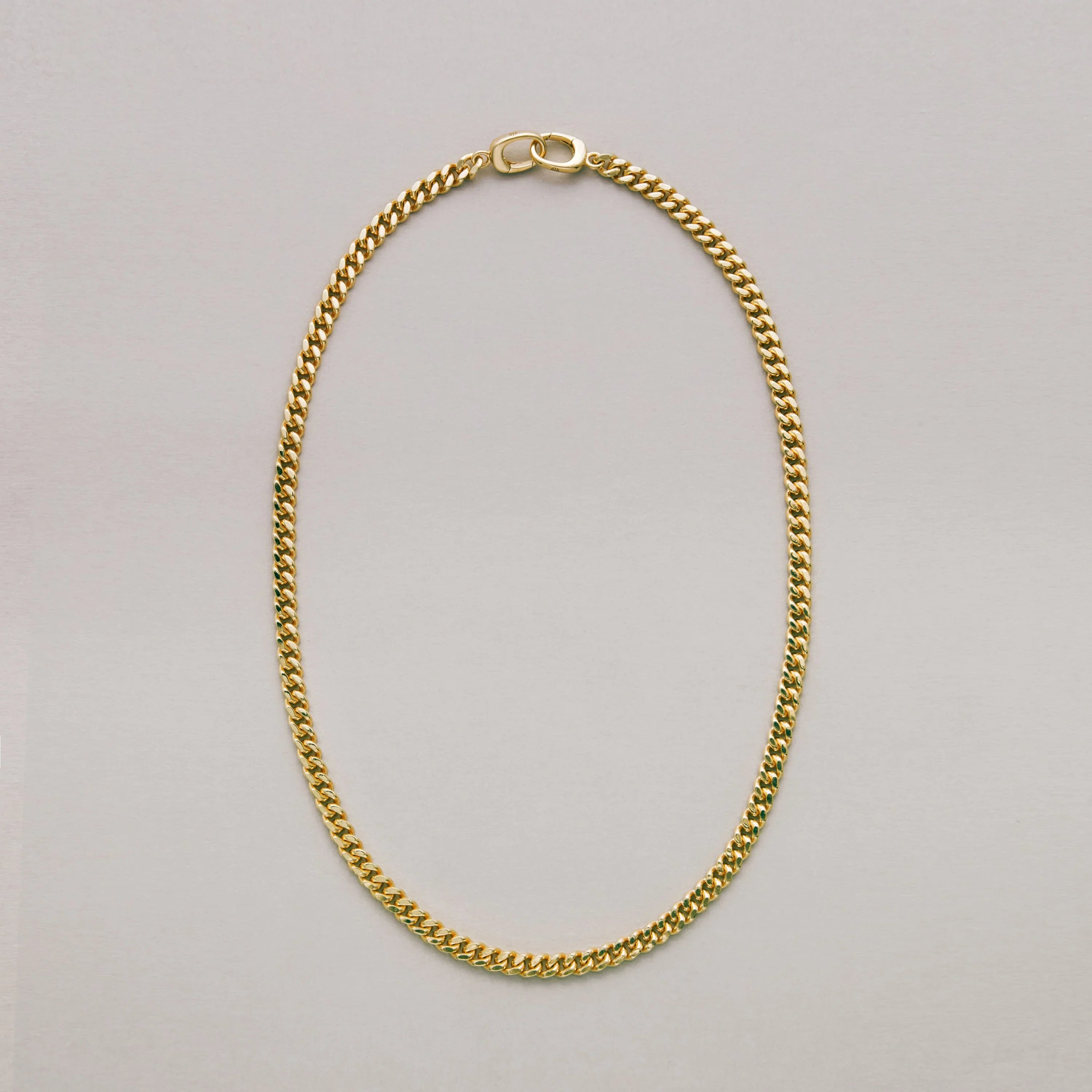 Sleek gold Cuban chain necklace on a light gray background