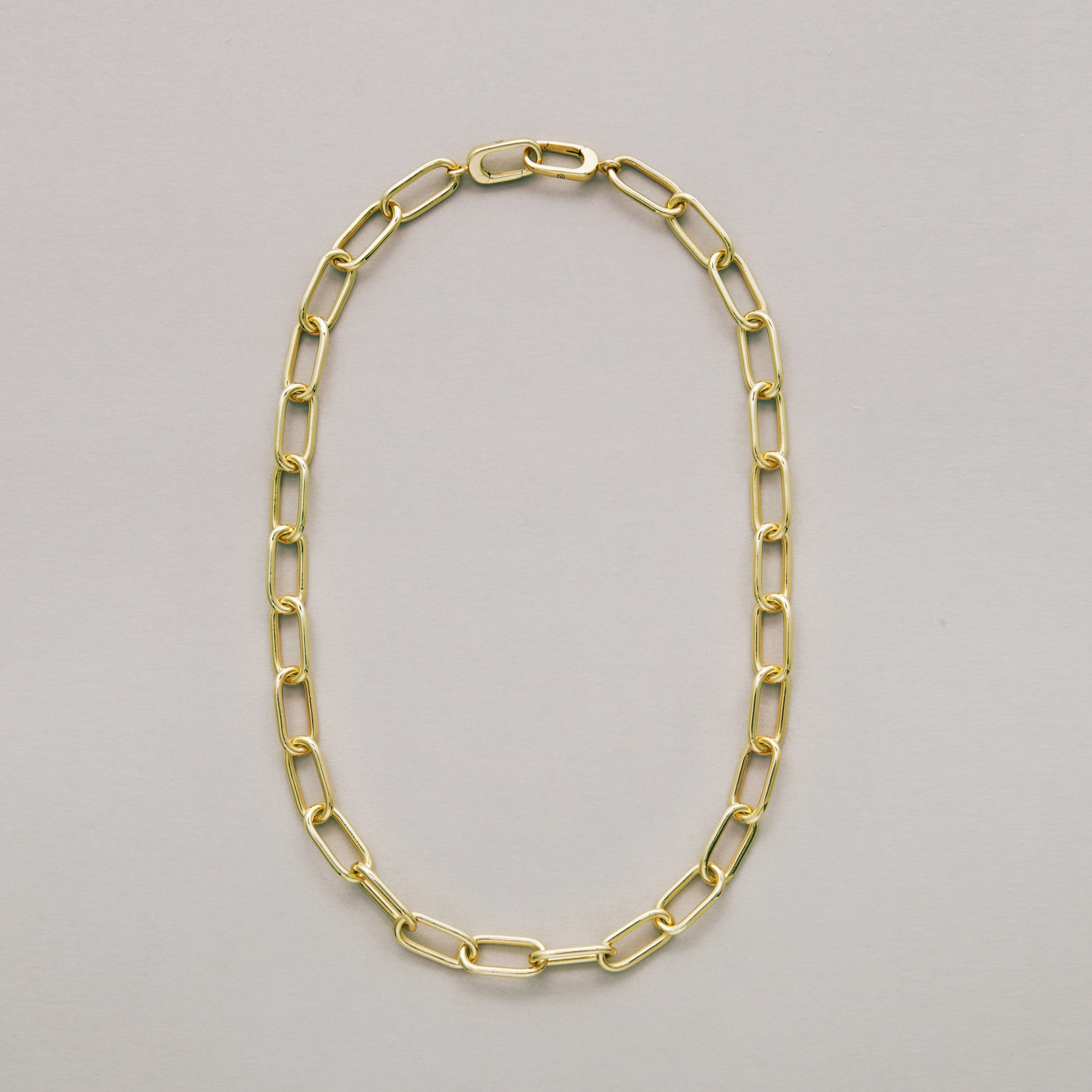 Gold thick paperclip chain necklace on a gray background