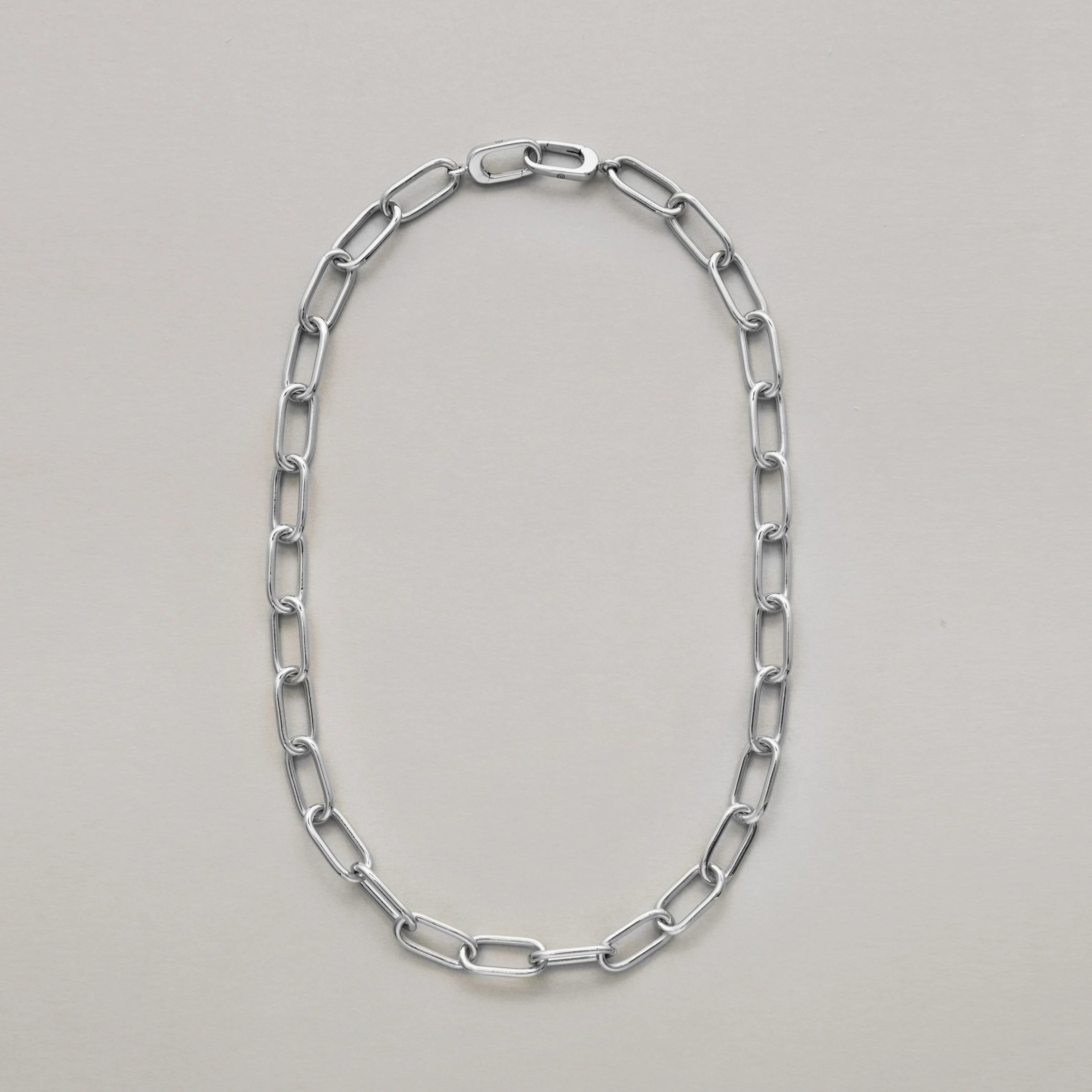 Thick silver paperclip chain necklace on light neutral background