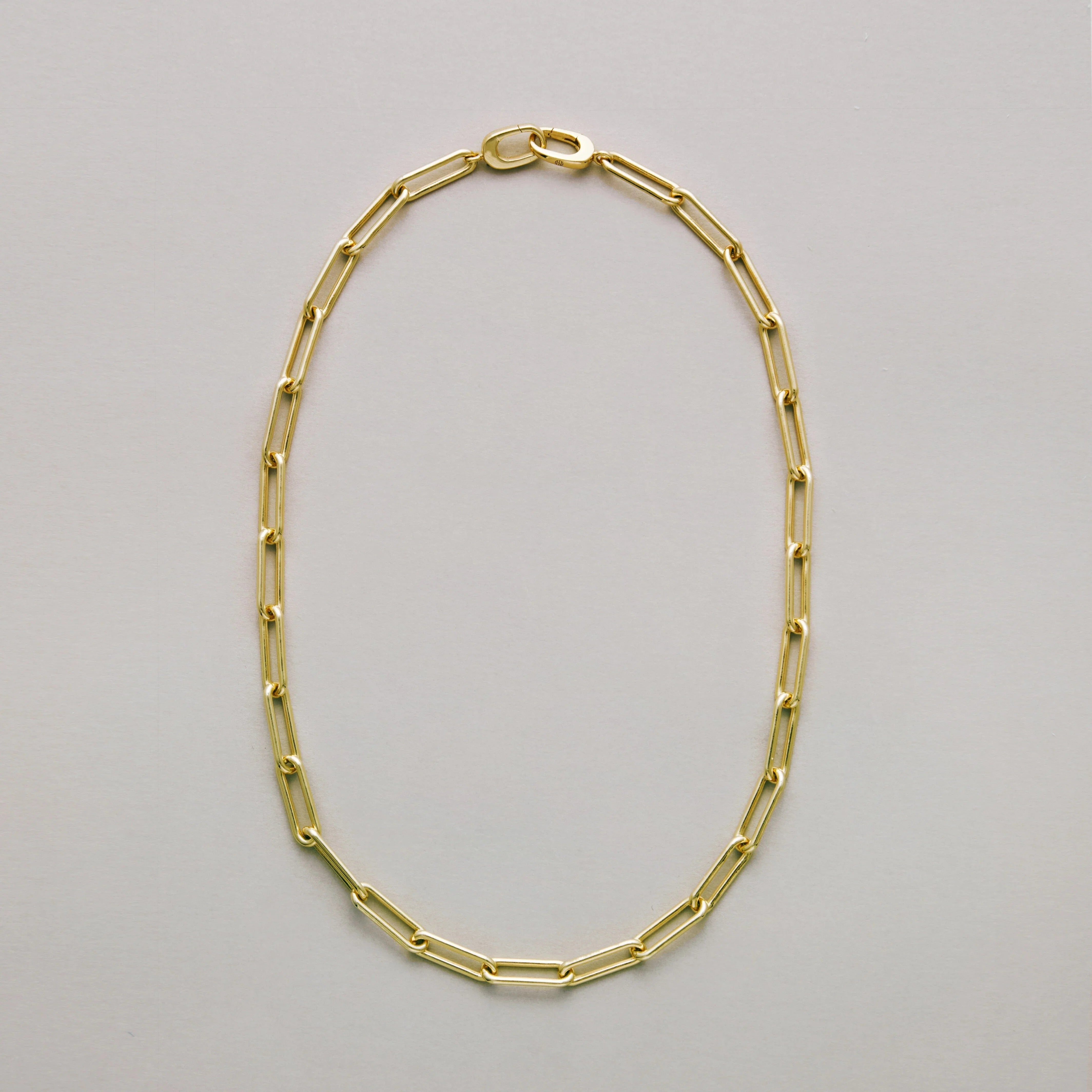Gold paperclip chain necklace on a light gray background