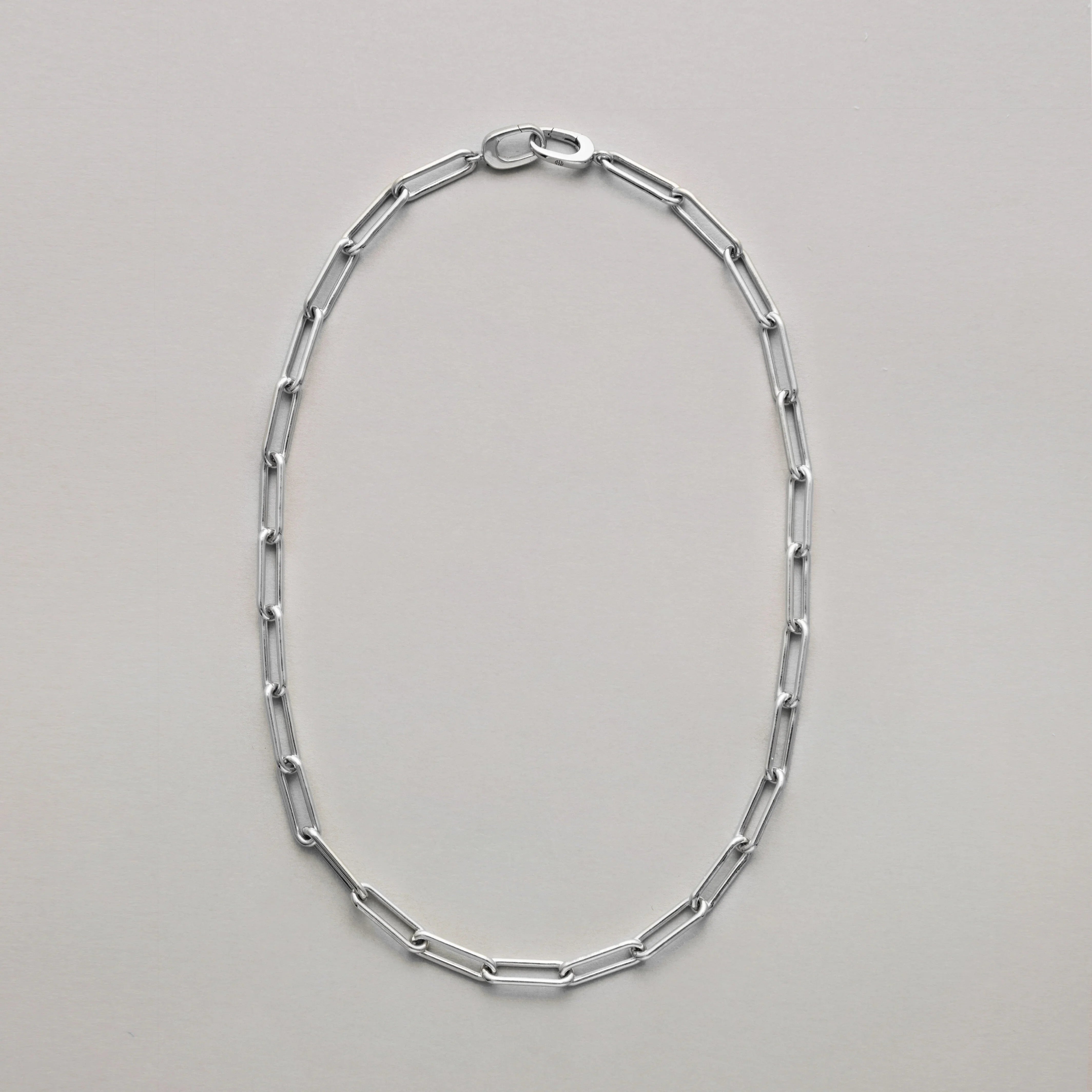 Silver paperclip chain necklace on a light gray background
