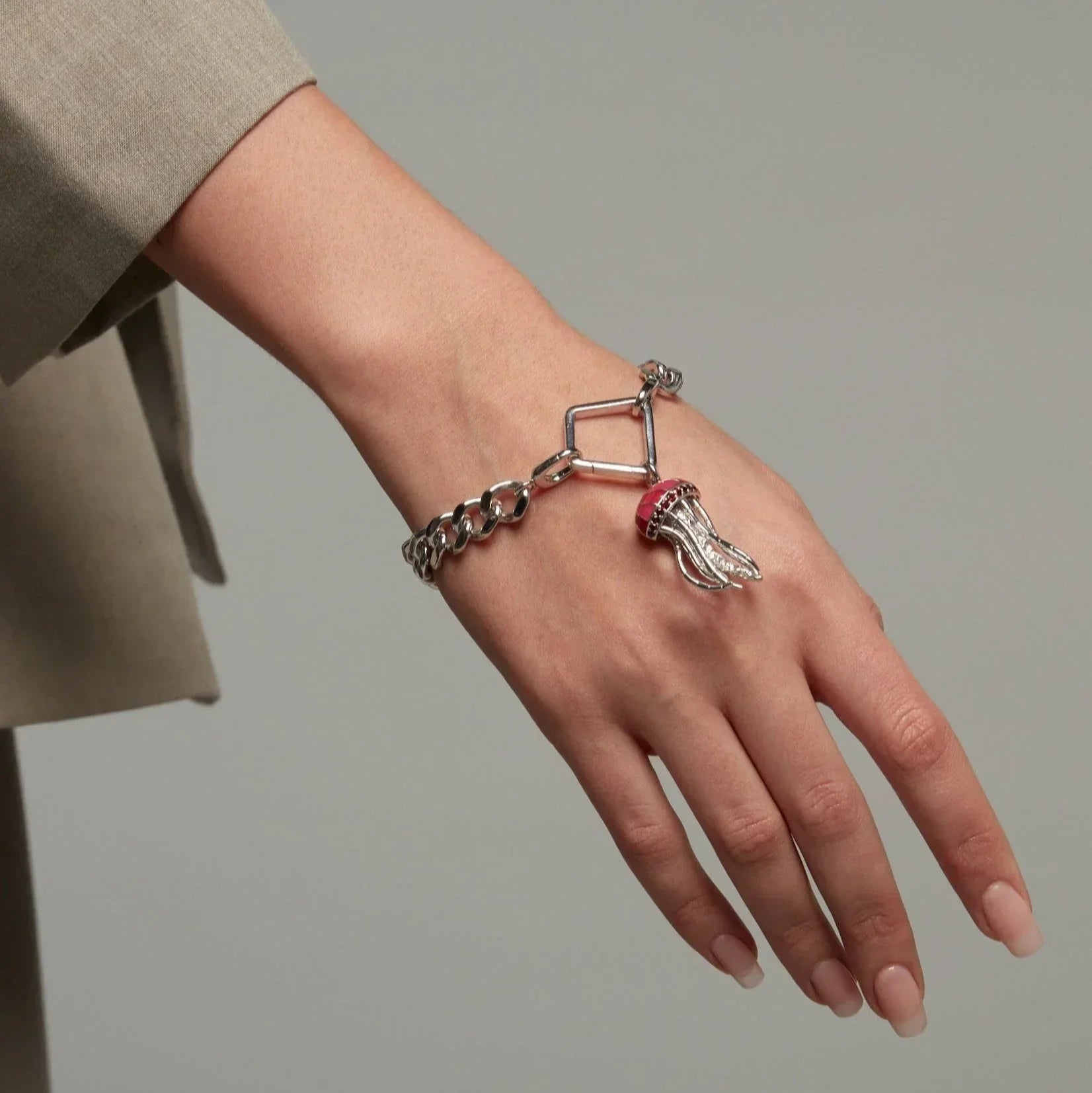 Silver chain bracelet featuring a dangling pink jellyfish charm on model's wrist.