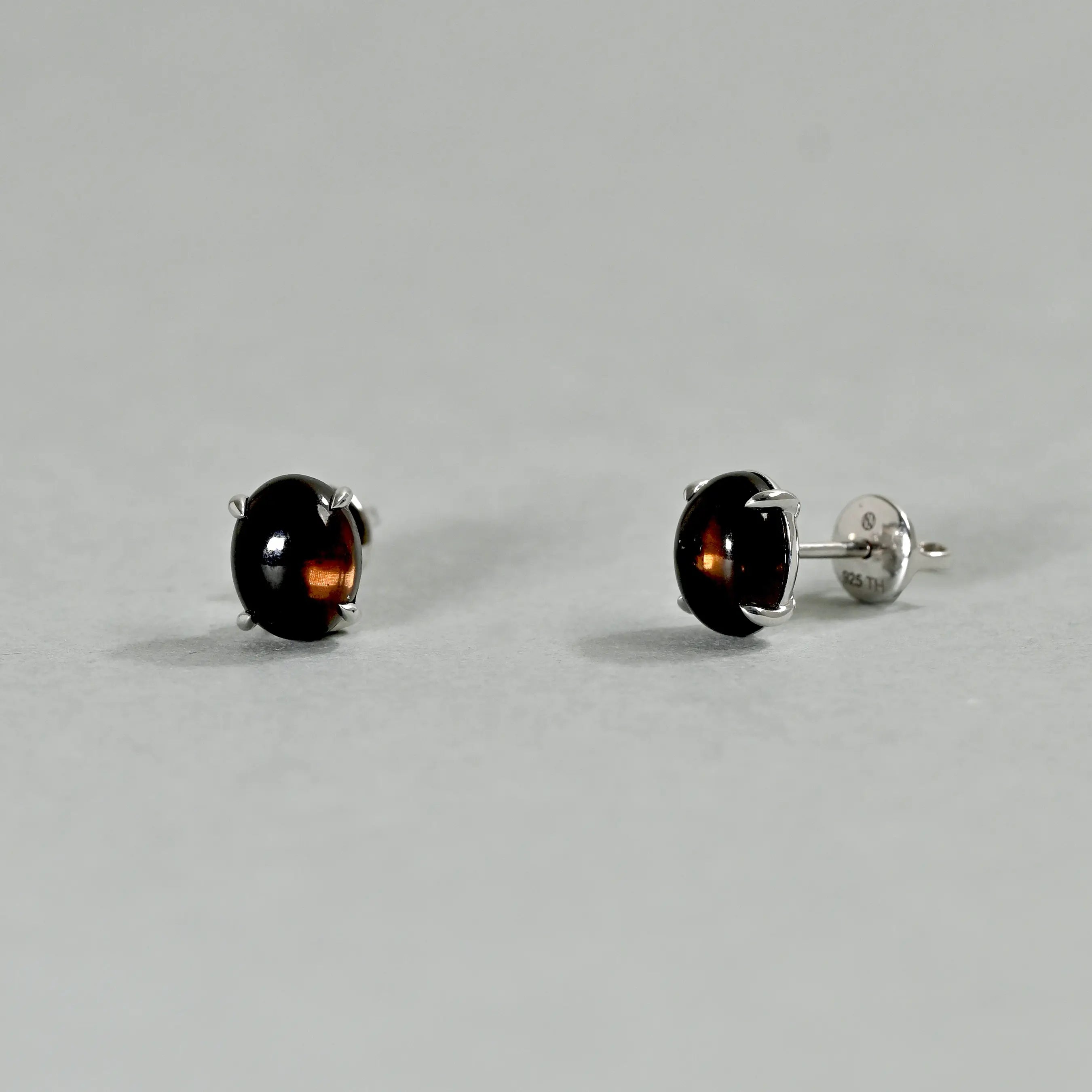 Pair of black stud earrings on a gray background