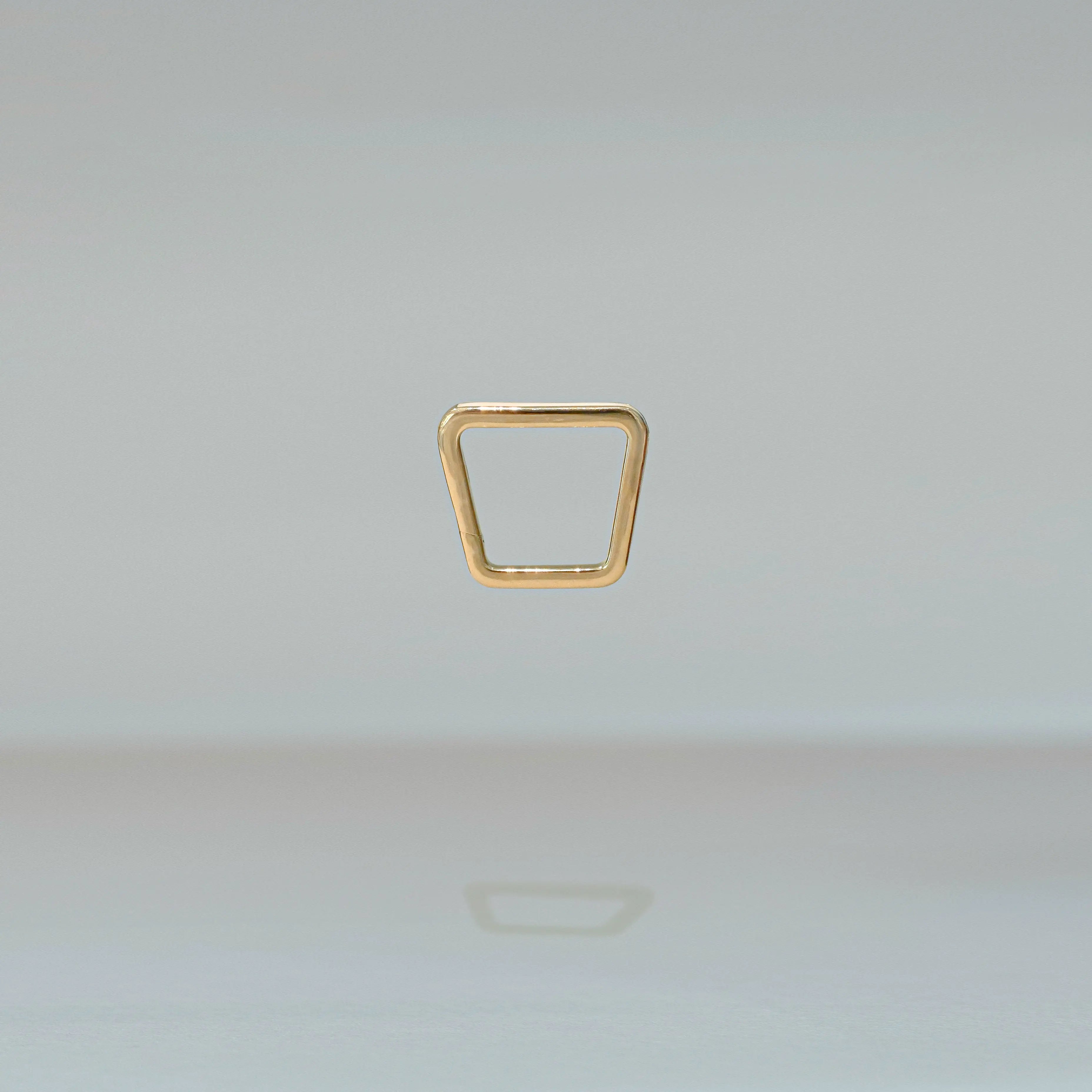 Gold ring with a geometric design on a light gray background