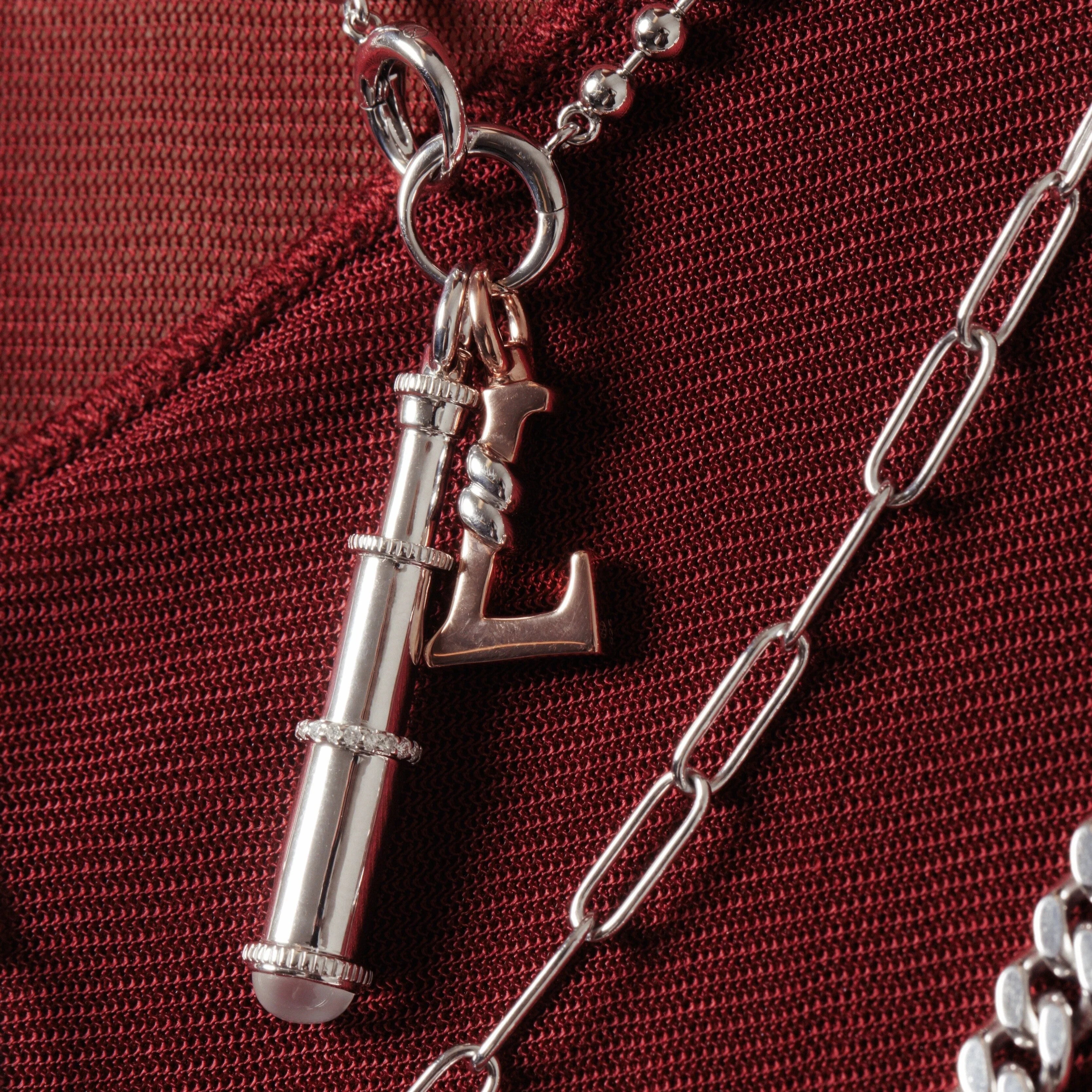 Silver telescope and initial letter L charms styled on layered chains.