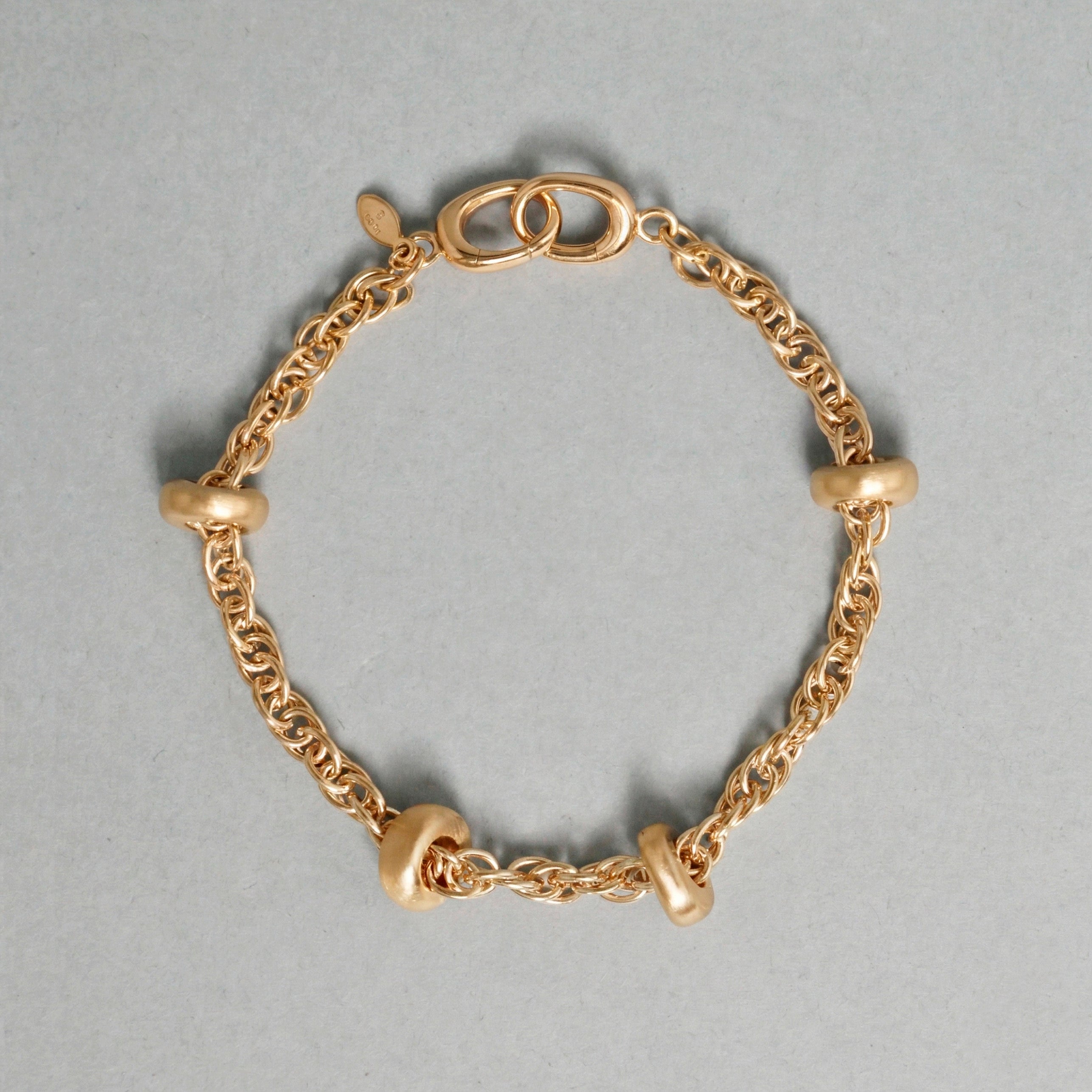 Gold chain bracelet on a gray background