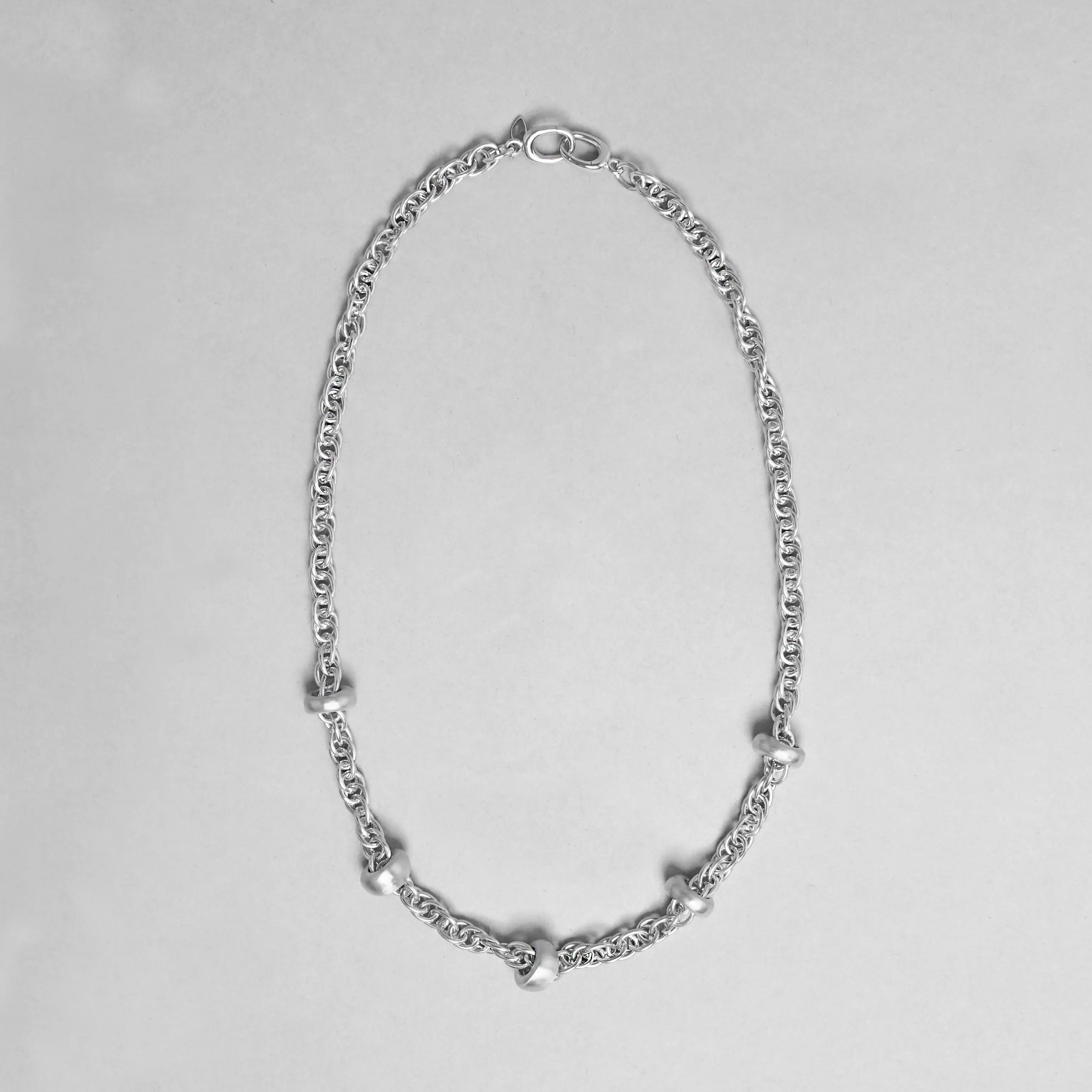 Silver chain necklace on a light gray background