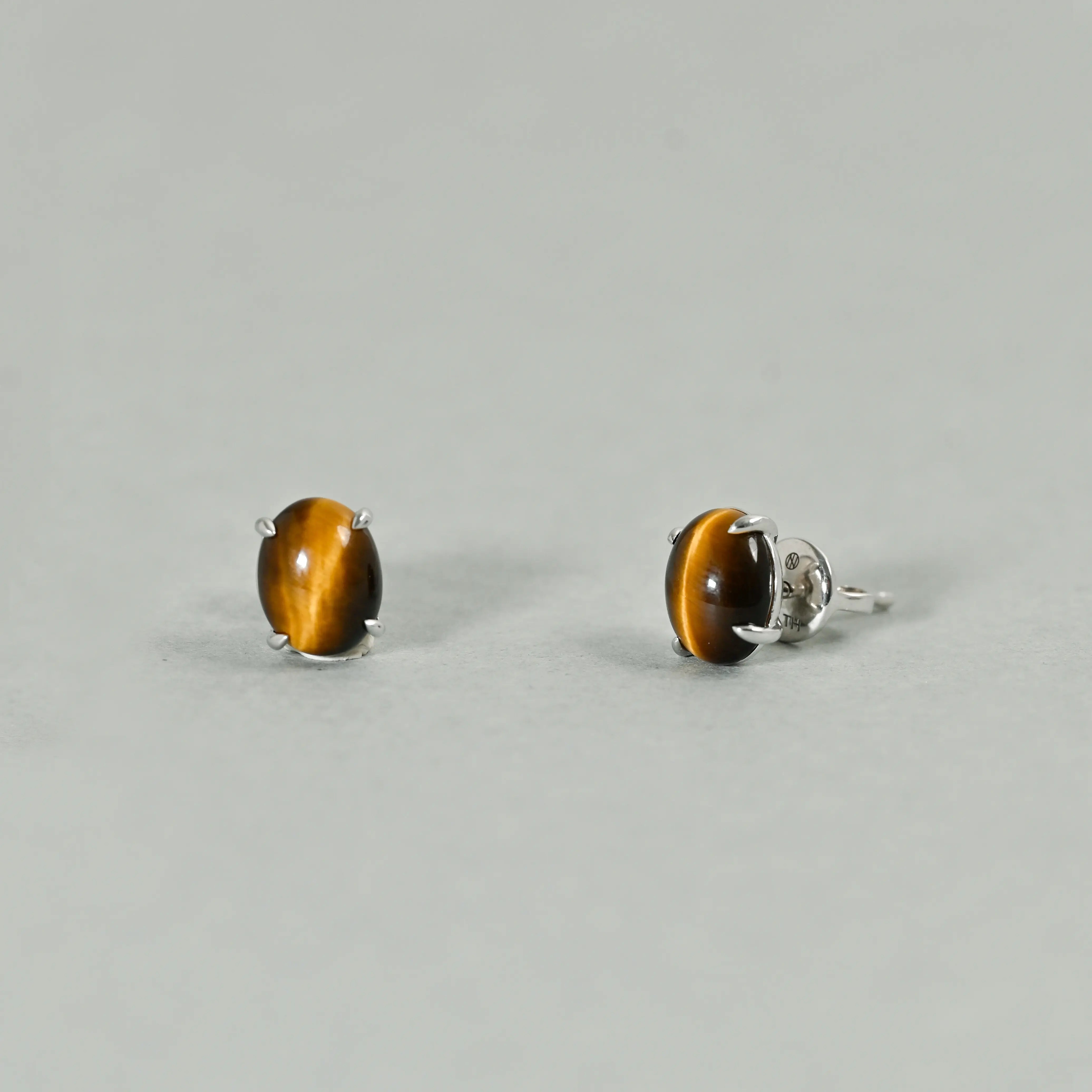 Pair of tiger eye stud earrings on a light gray background