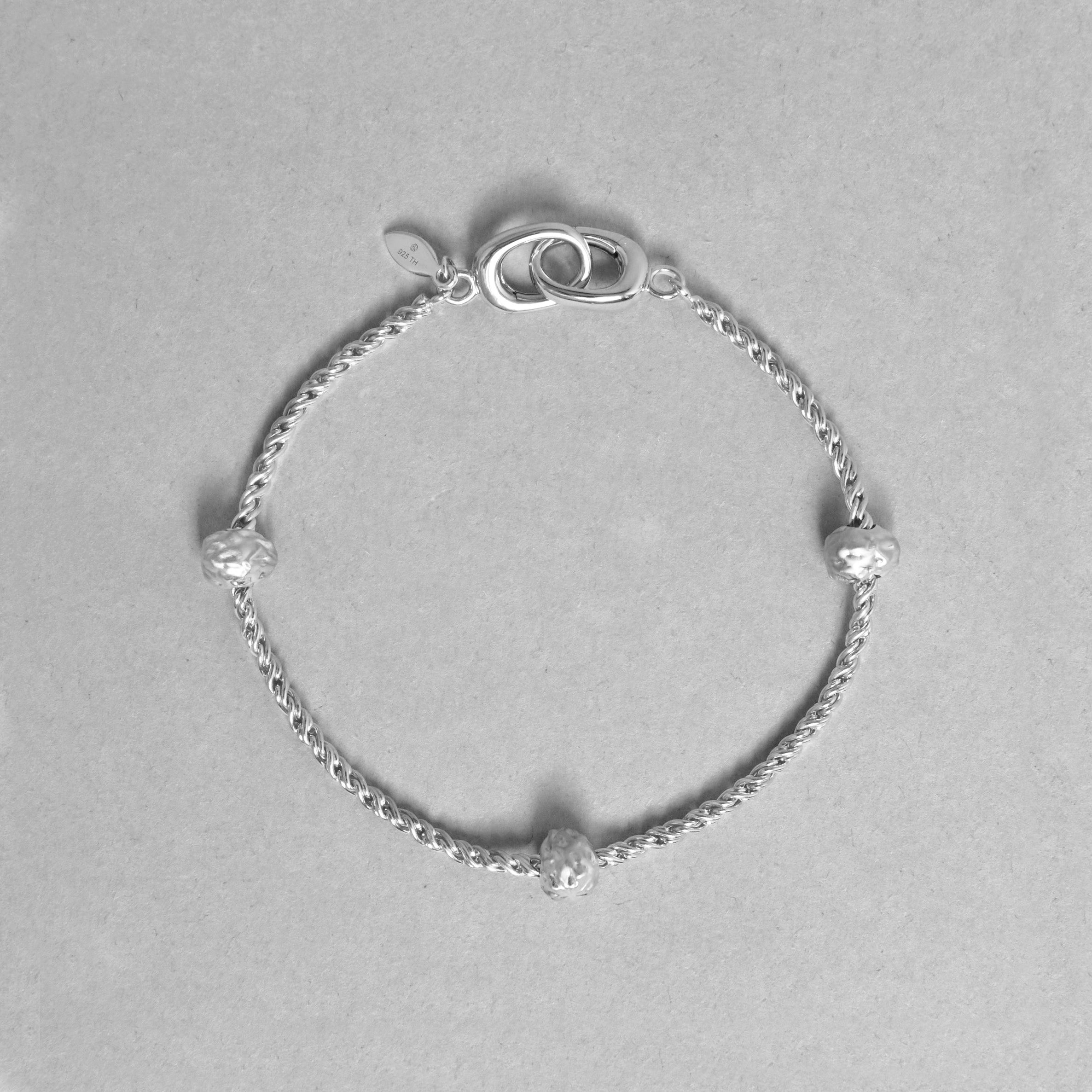 Silver bracelet with small beads on a gray background