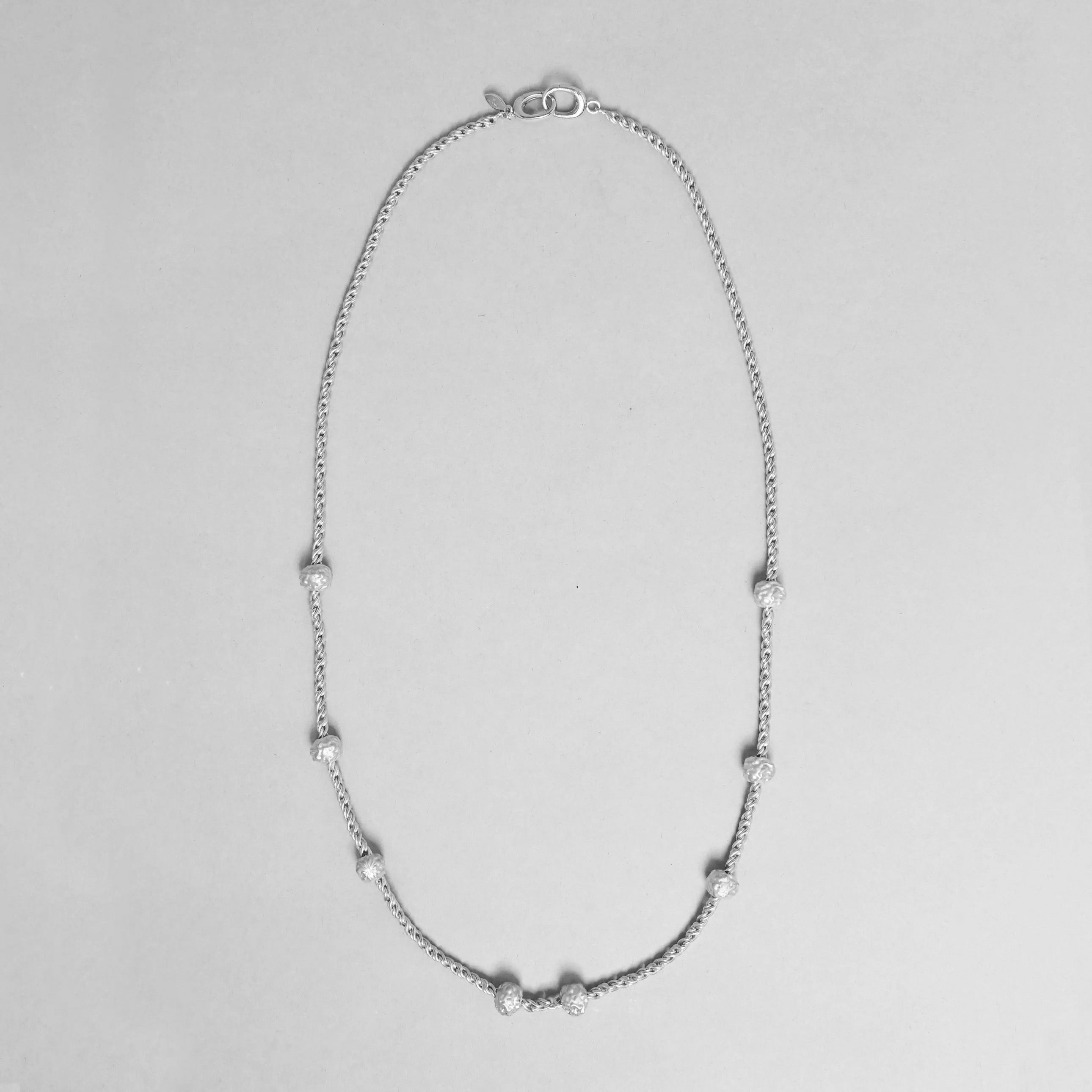 Silver necklace with small beads on a light gray background