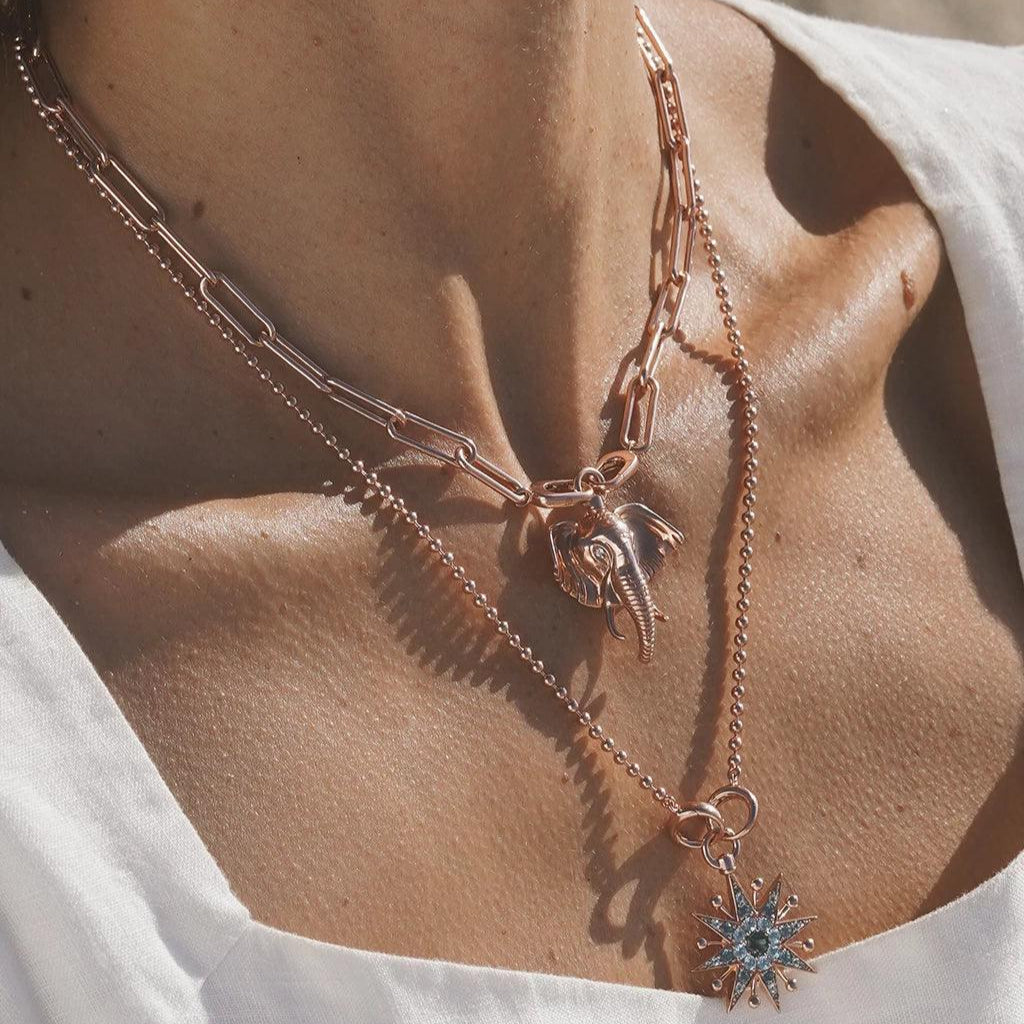 Layered rose gold necklaces with elephant and starburst charms