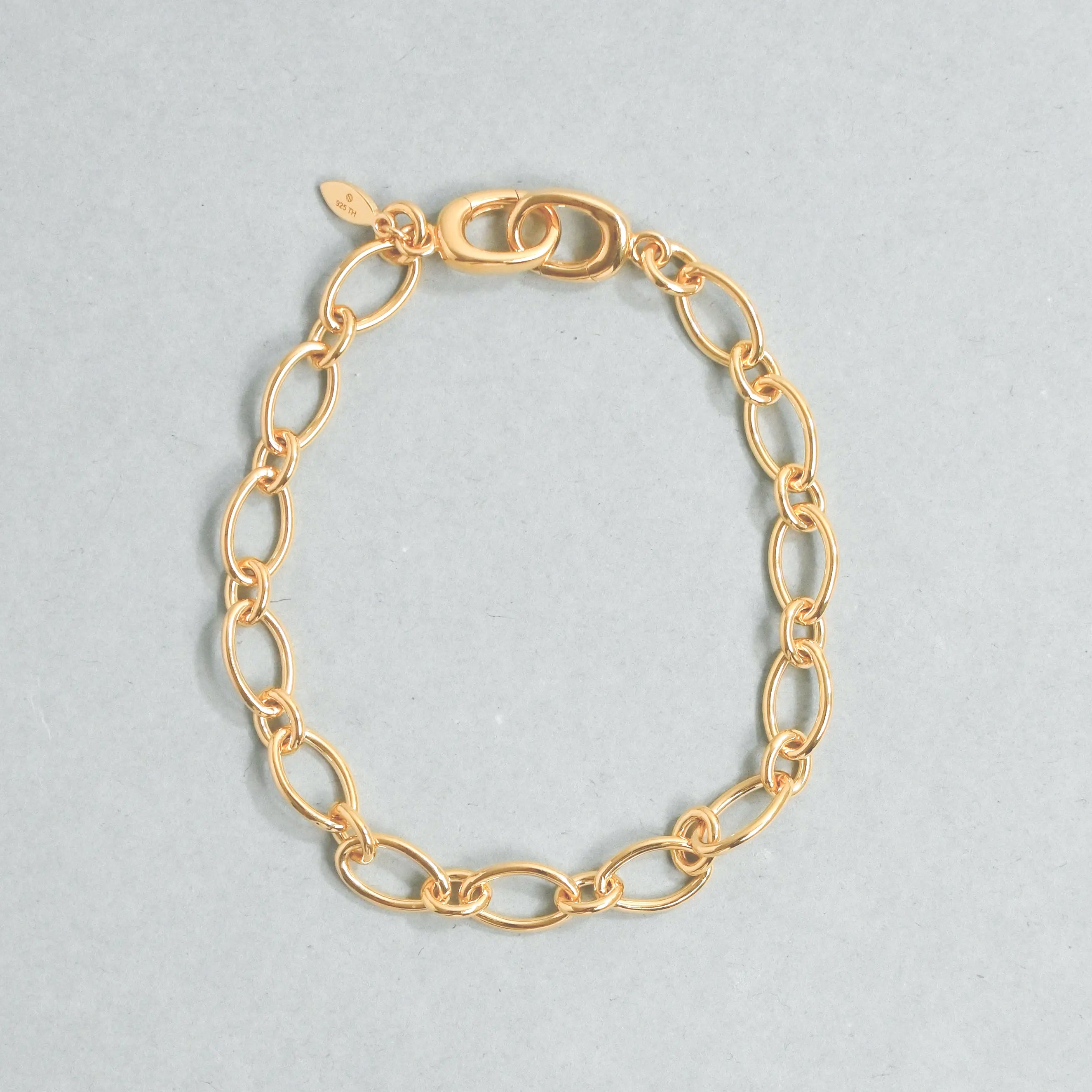 Gold chain bracelet on a light gray background