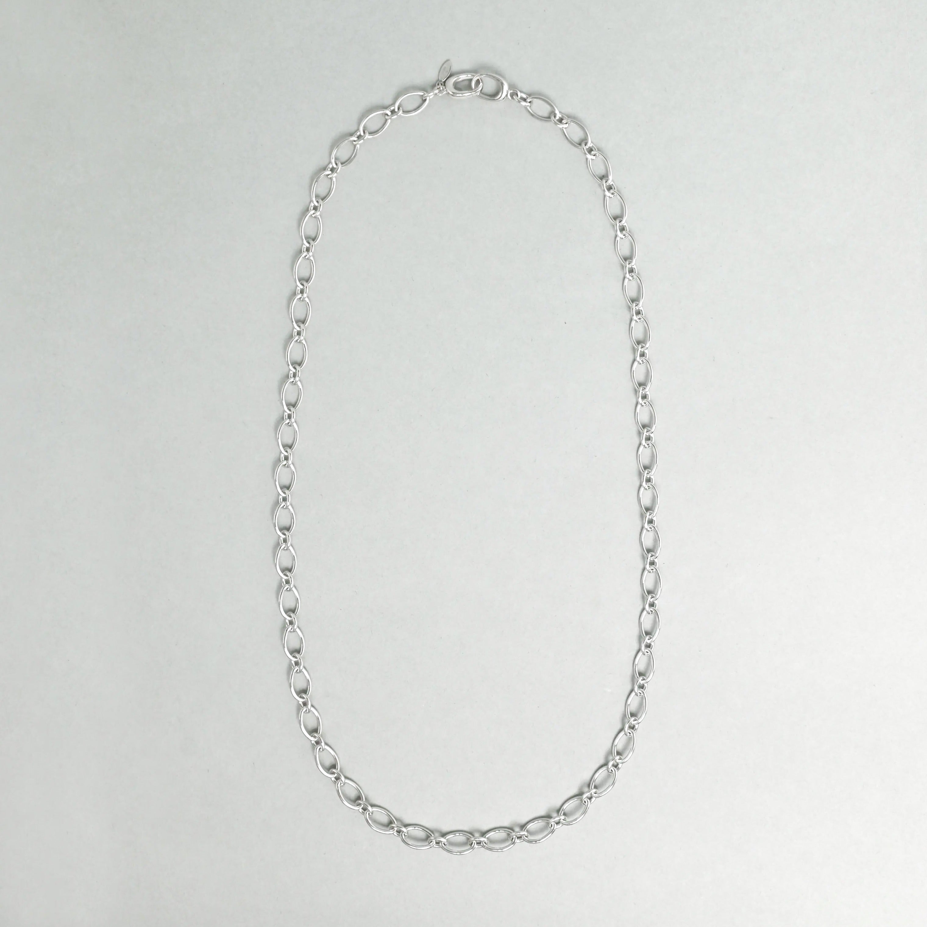 Silver chain necklace on a light gray background