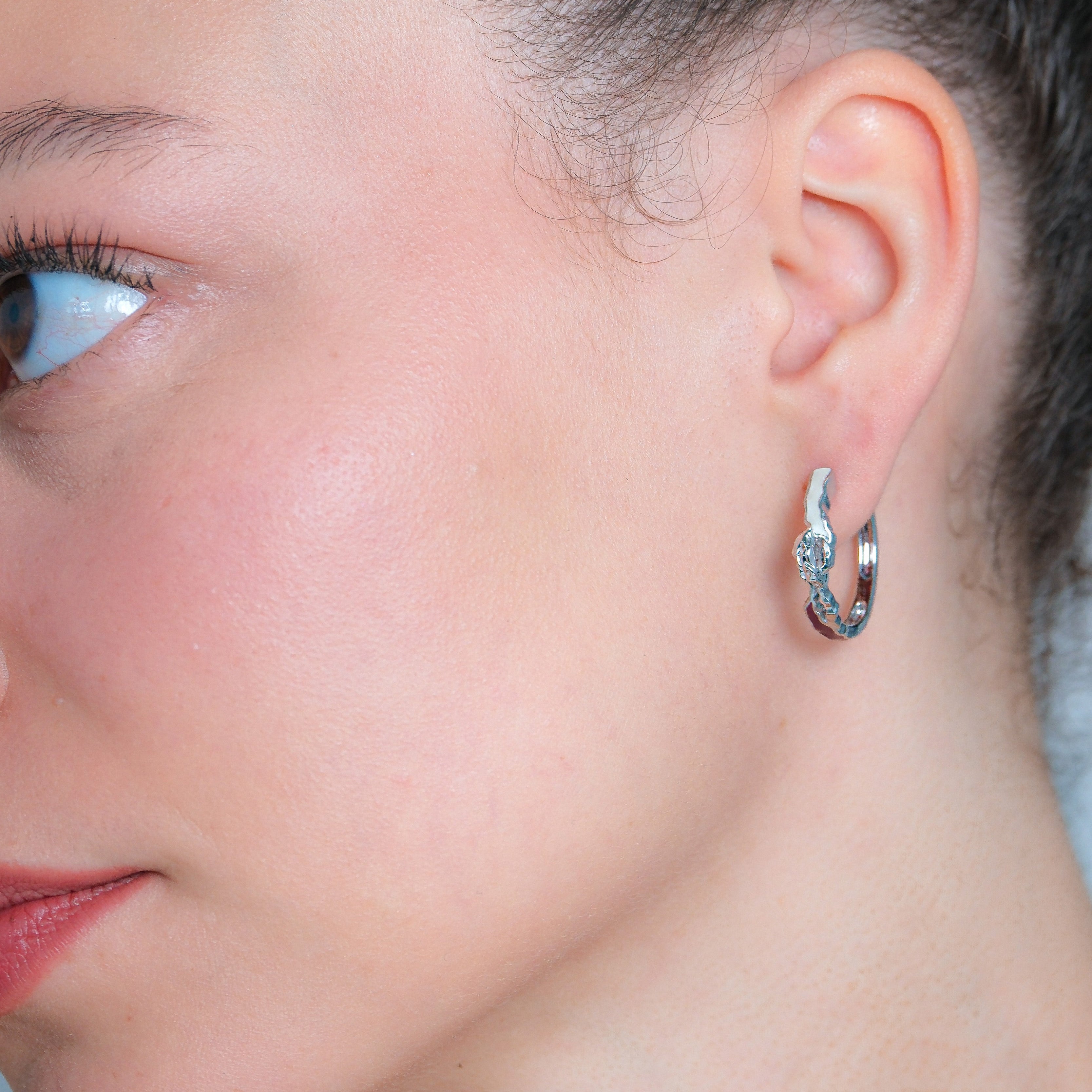 Close-up of a person wearing a silver hoop earring.