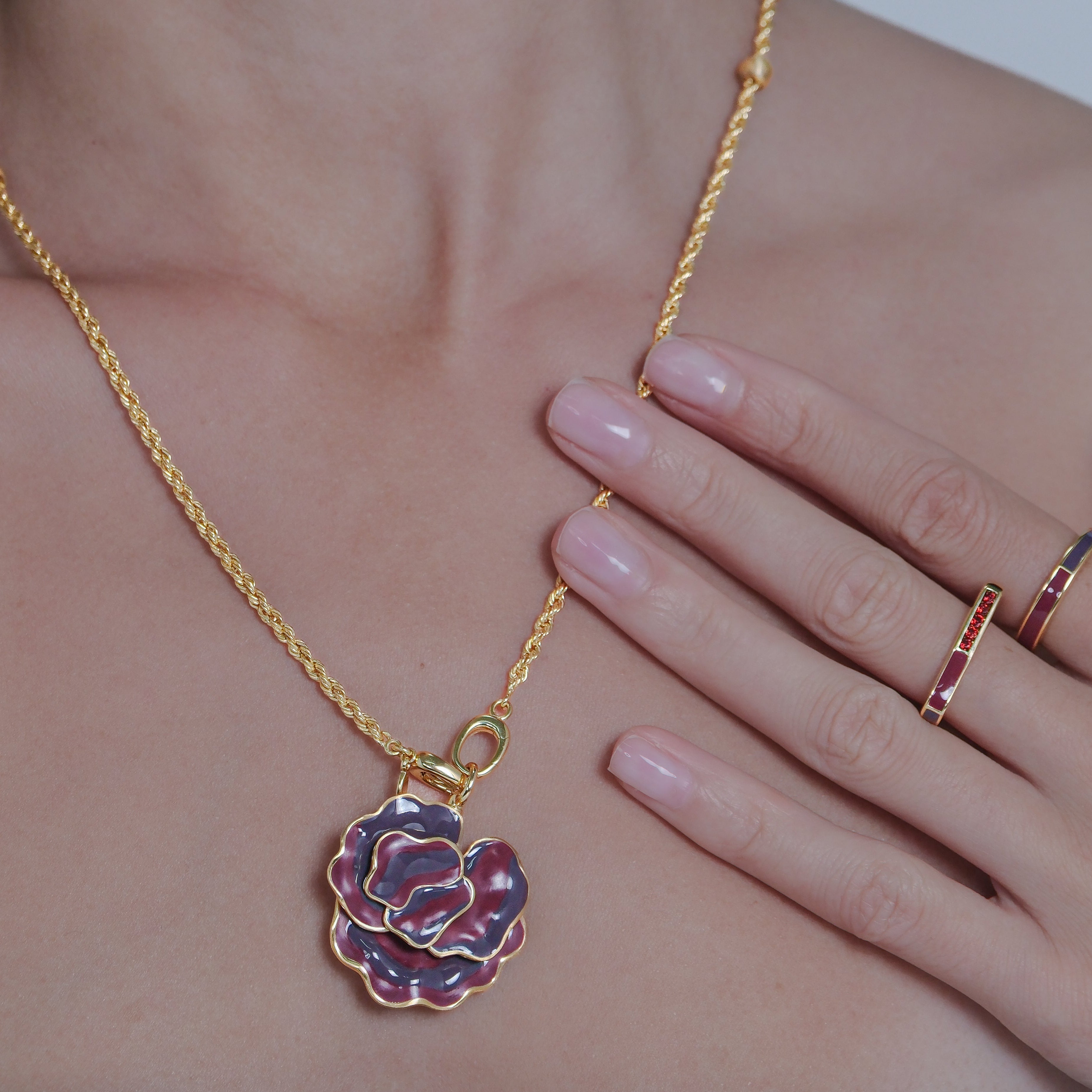 Gold necklace with a floral pendant worn by a person