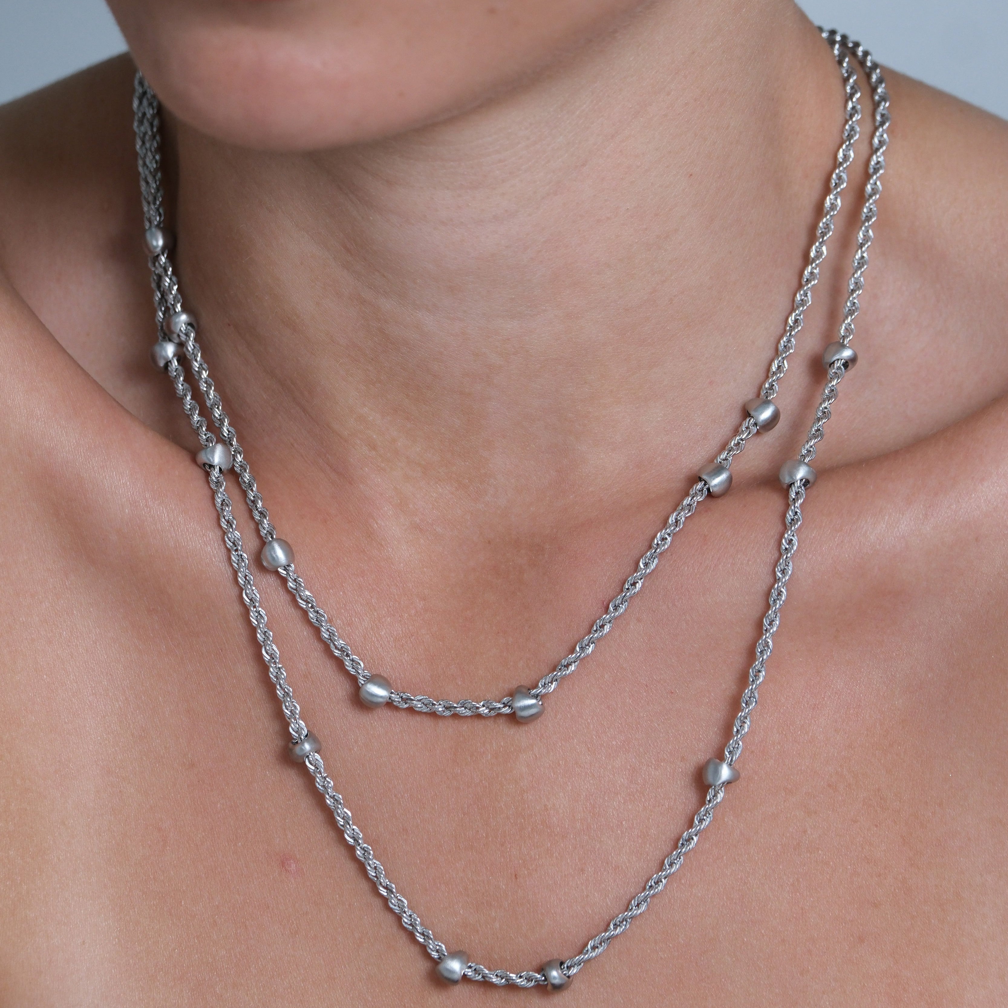 Close-up of a woman wearing a silver necklace with a blurred background