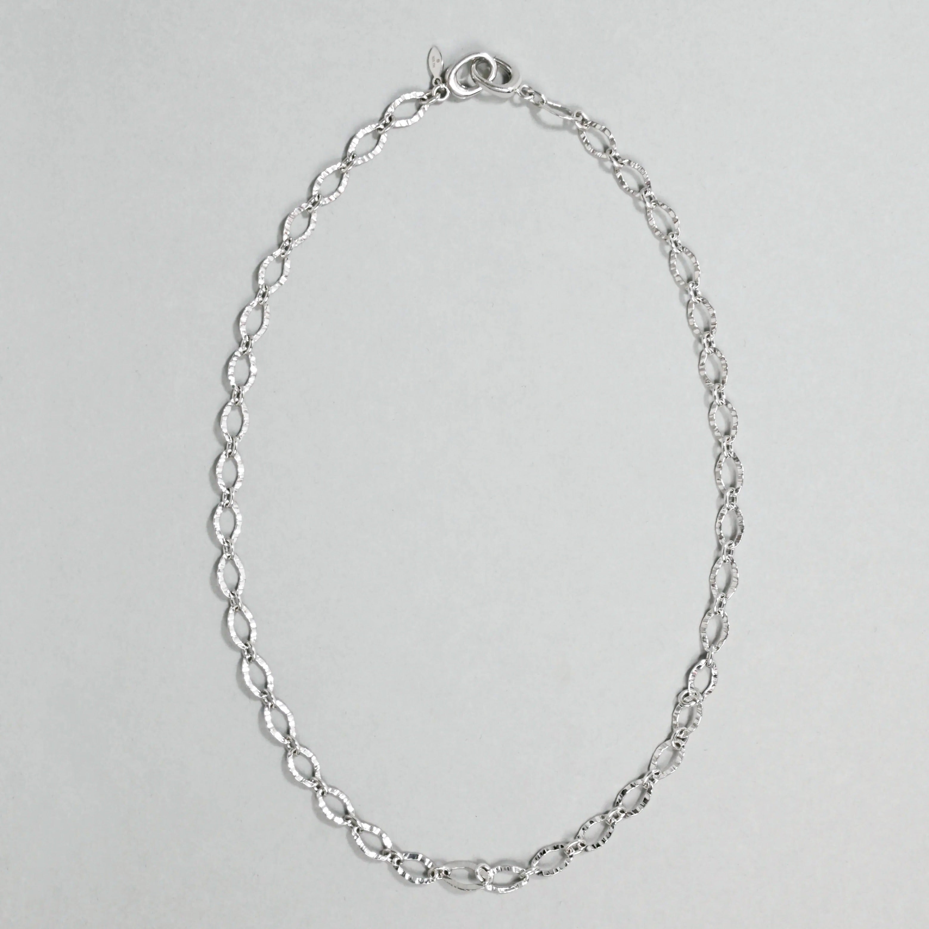 Silver chain necklace on a light gray background