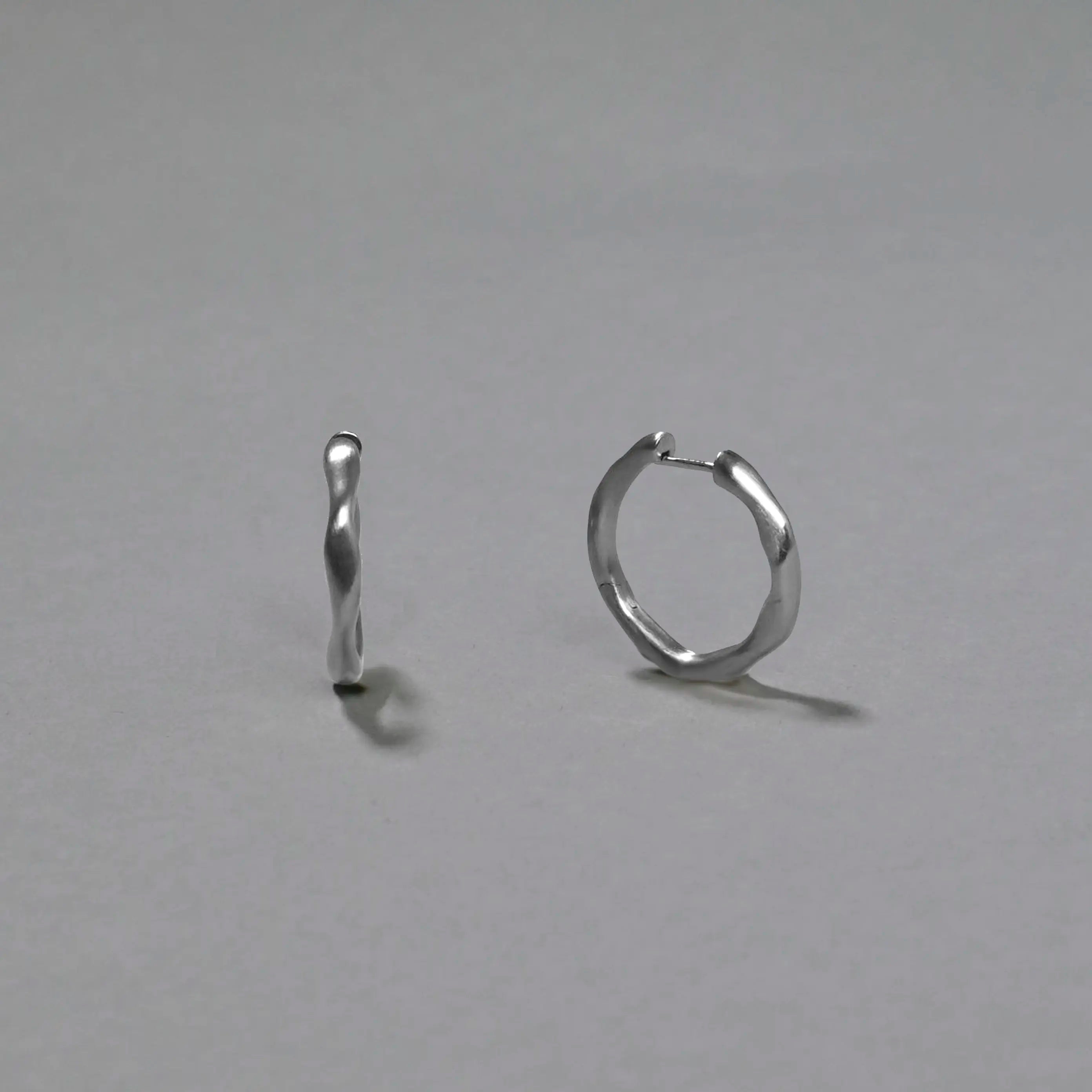 Pair of silver hoop earrings on a gray background