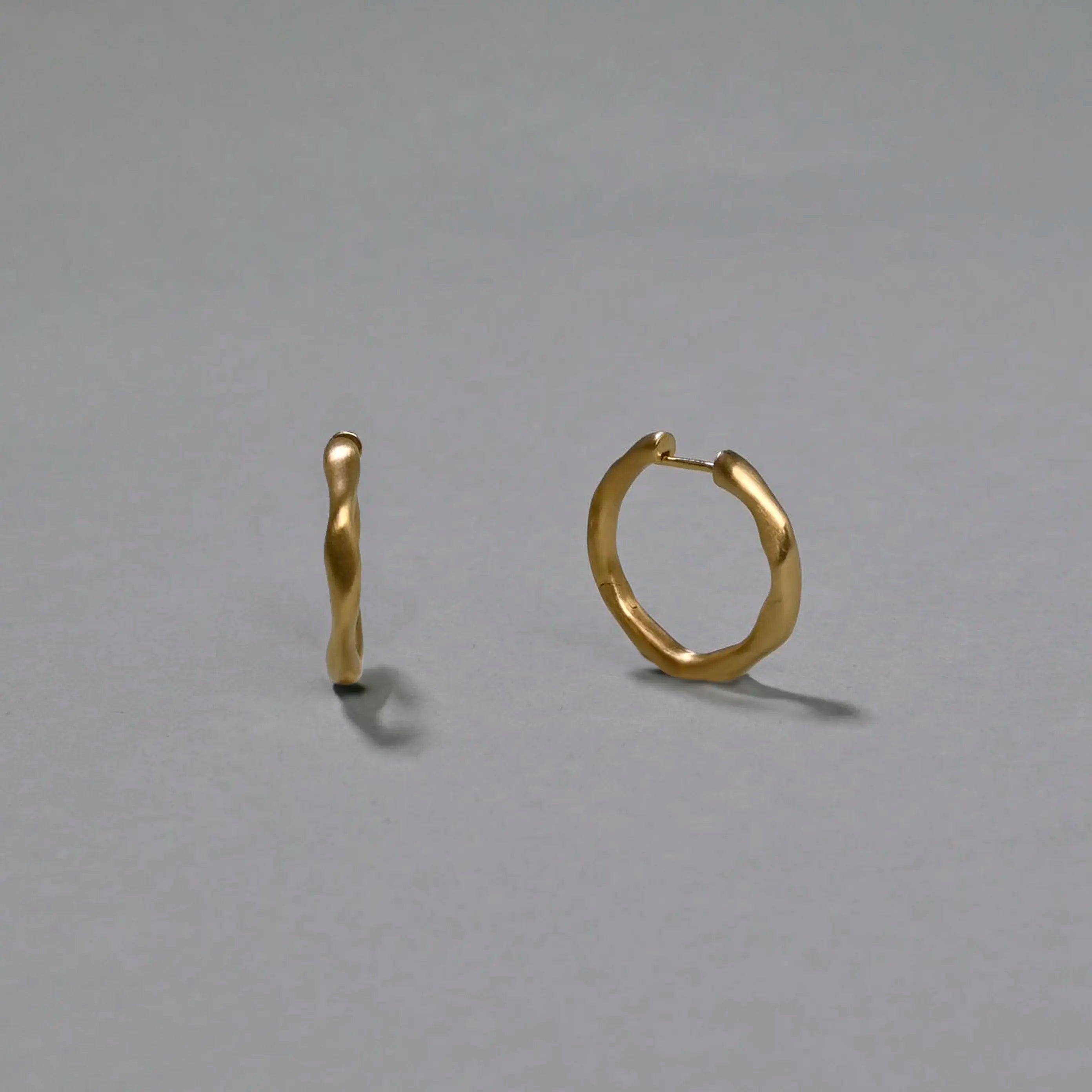 Gold hoop earrings on a gray background