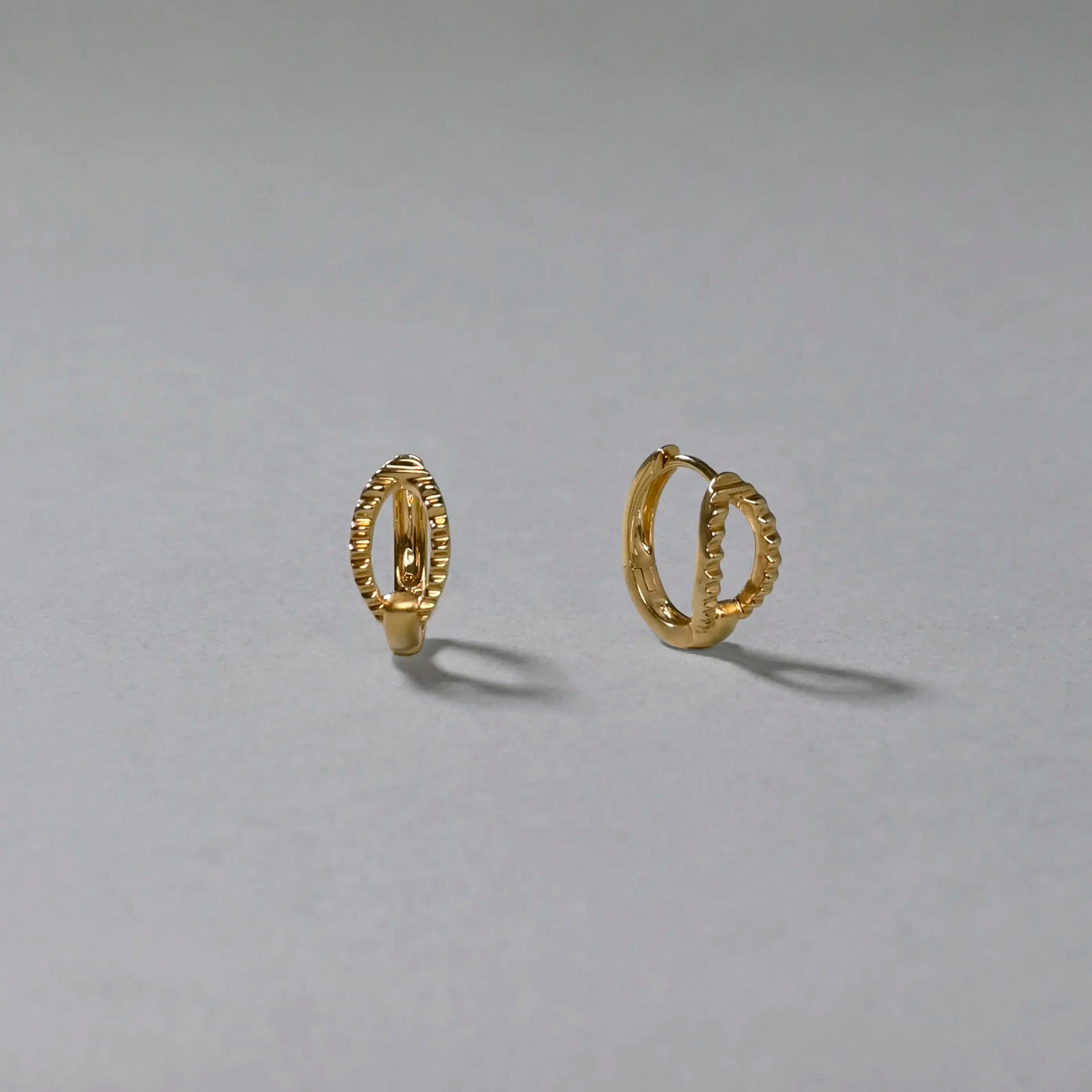 Gold hoop earrings on a gray background
