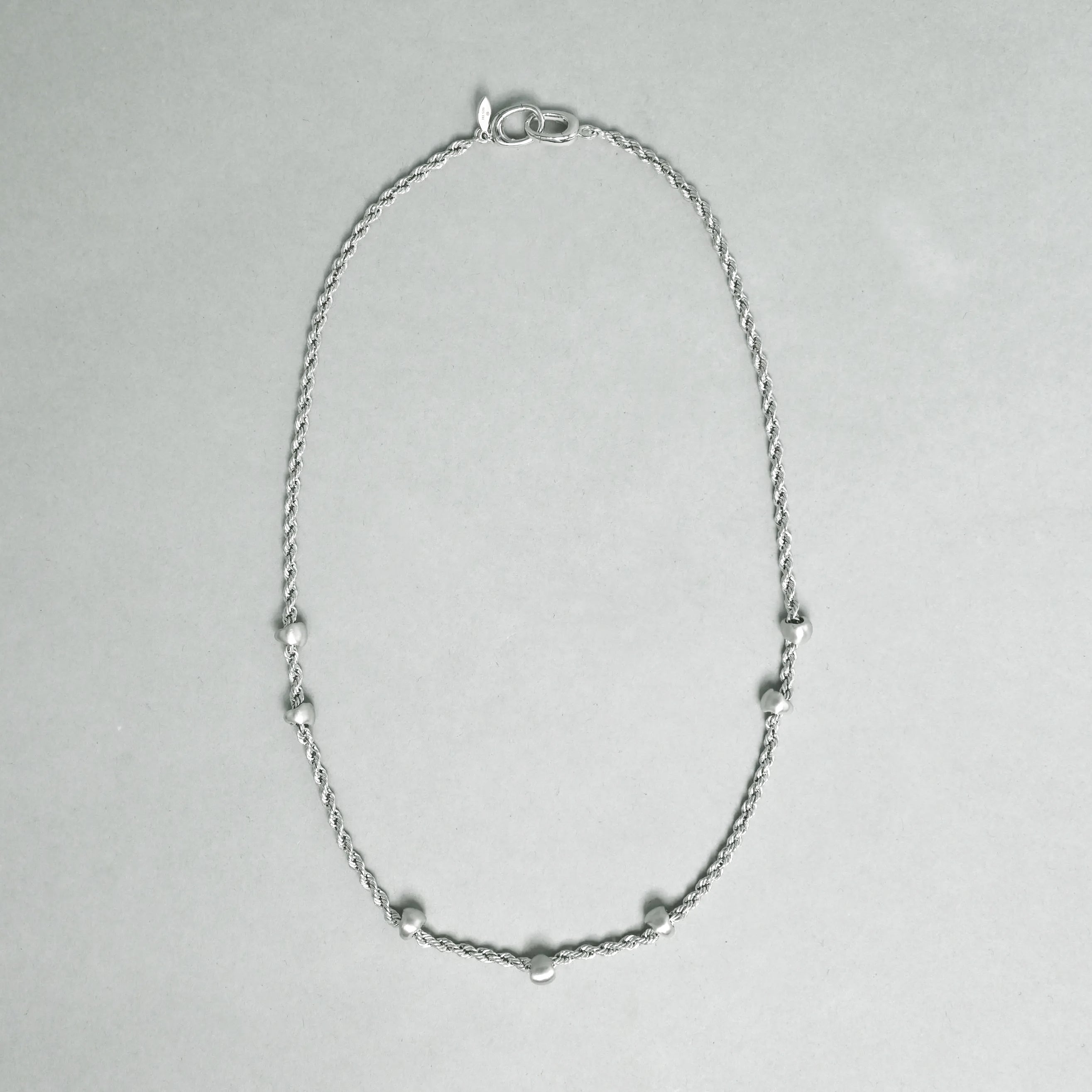 Silver necklace on a light gray background