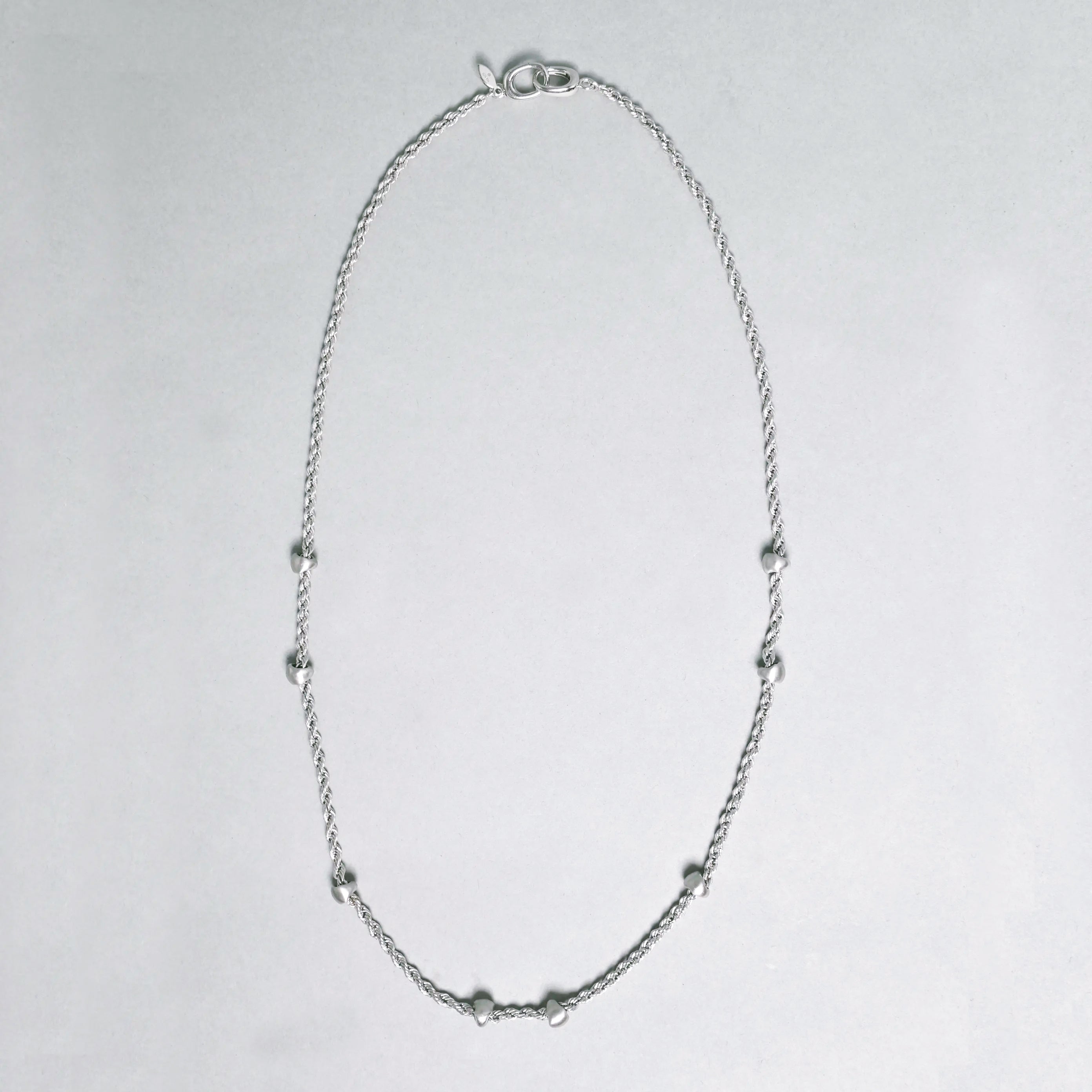 Silver necklace on a light gray background