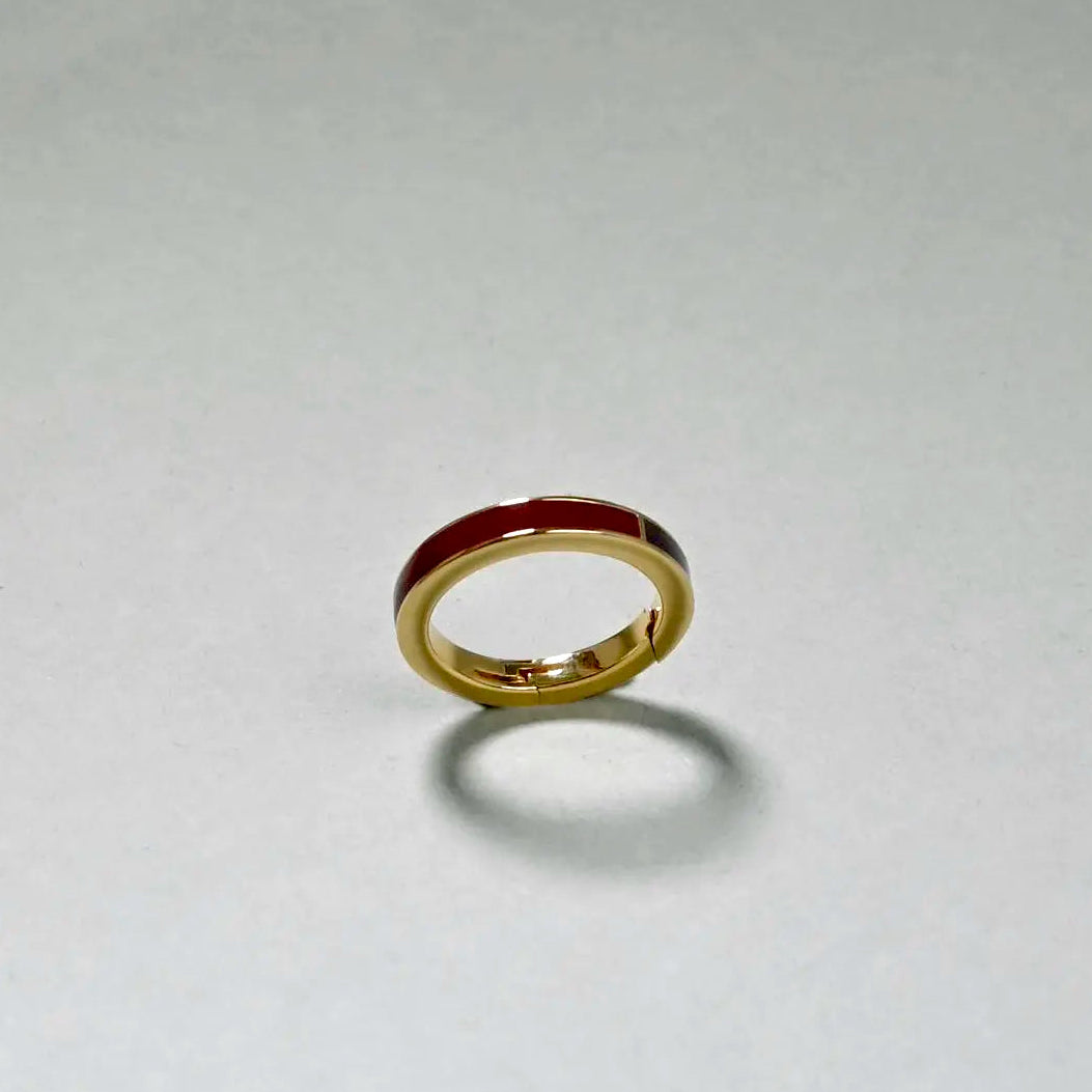 Gold ring with a red center on a light gray background