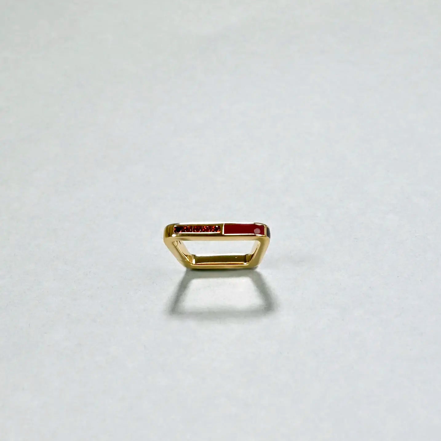 Gold ring with red stones on a light gray background