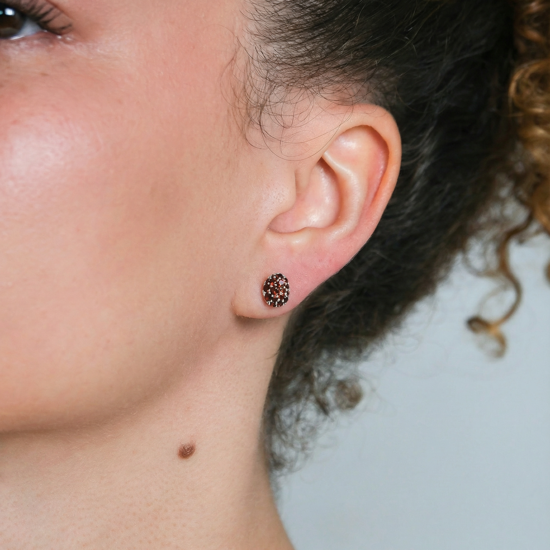 Close-up of an ear with a small earring against a neutral background