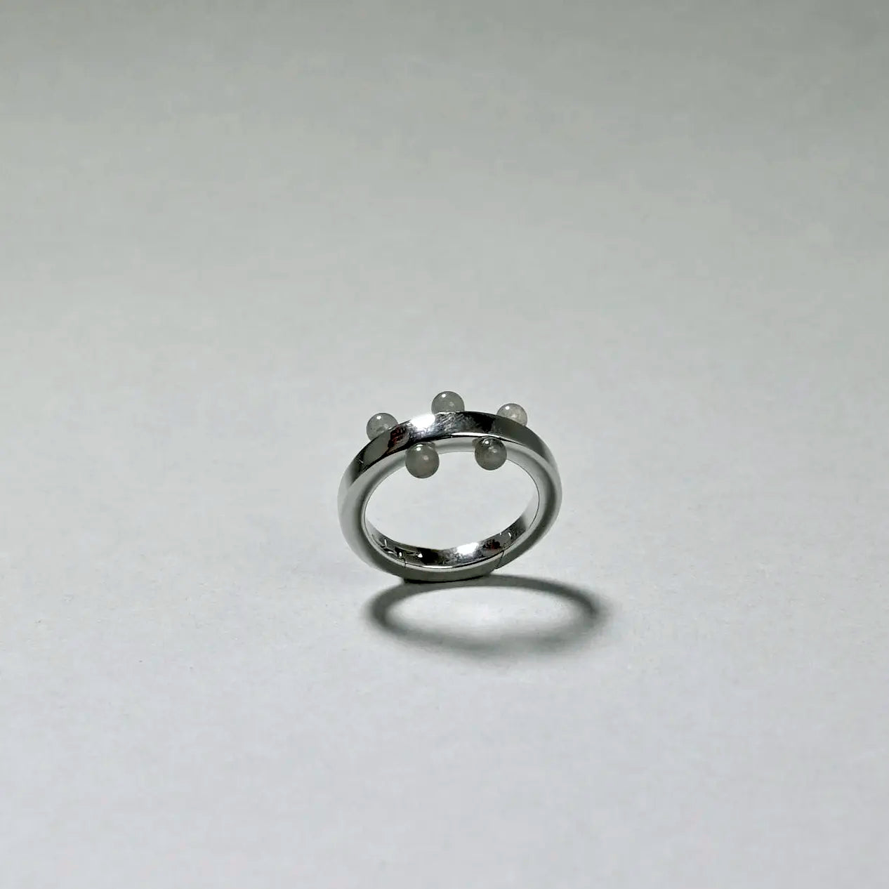 Silver ring with three small pearls on a light gray background