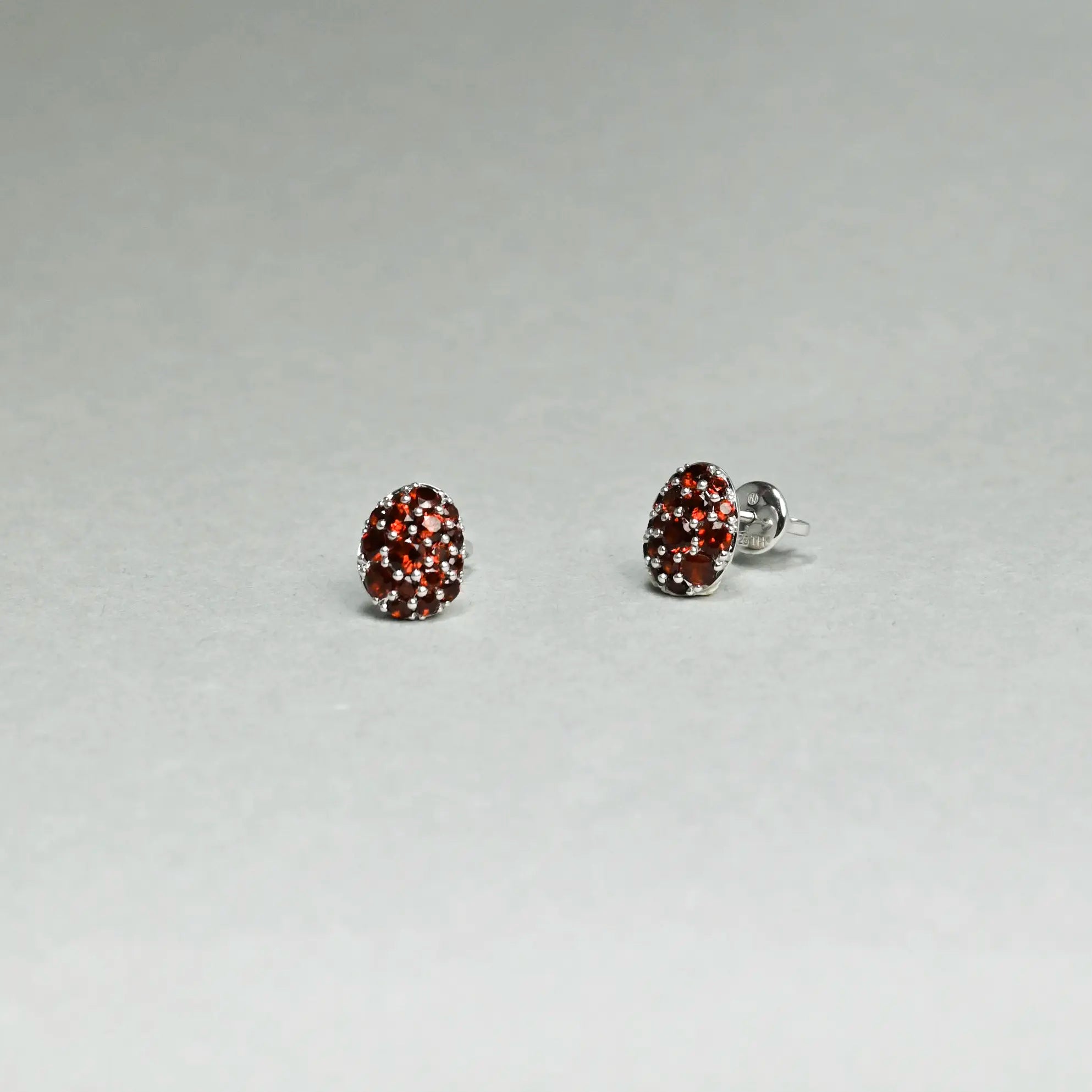 Pair of earrings with red gemstones on a gray background