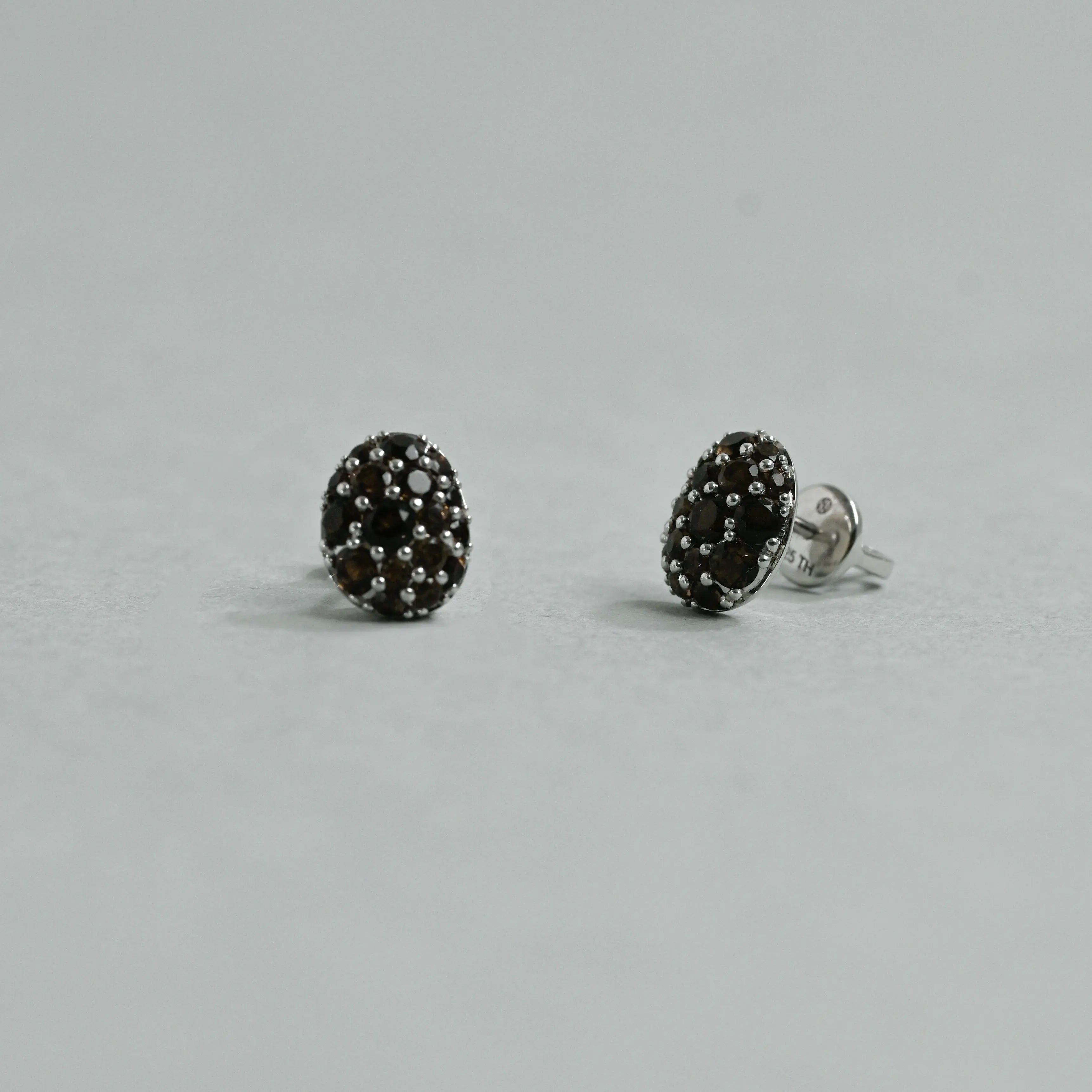 Pair of black stud earrings on a gray background
