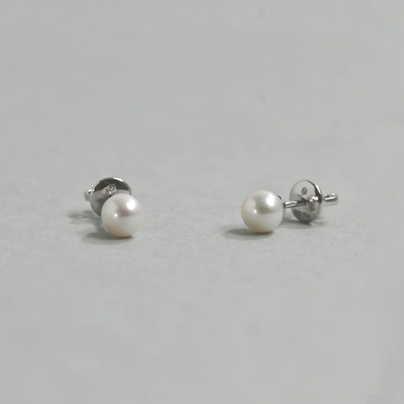 Pair of pearl stud earrings on a light gray background