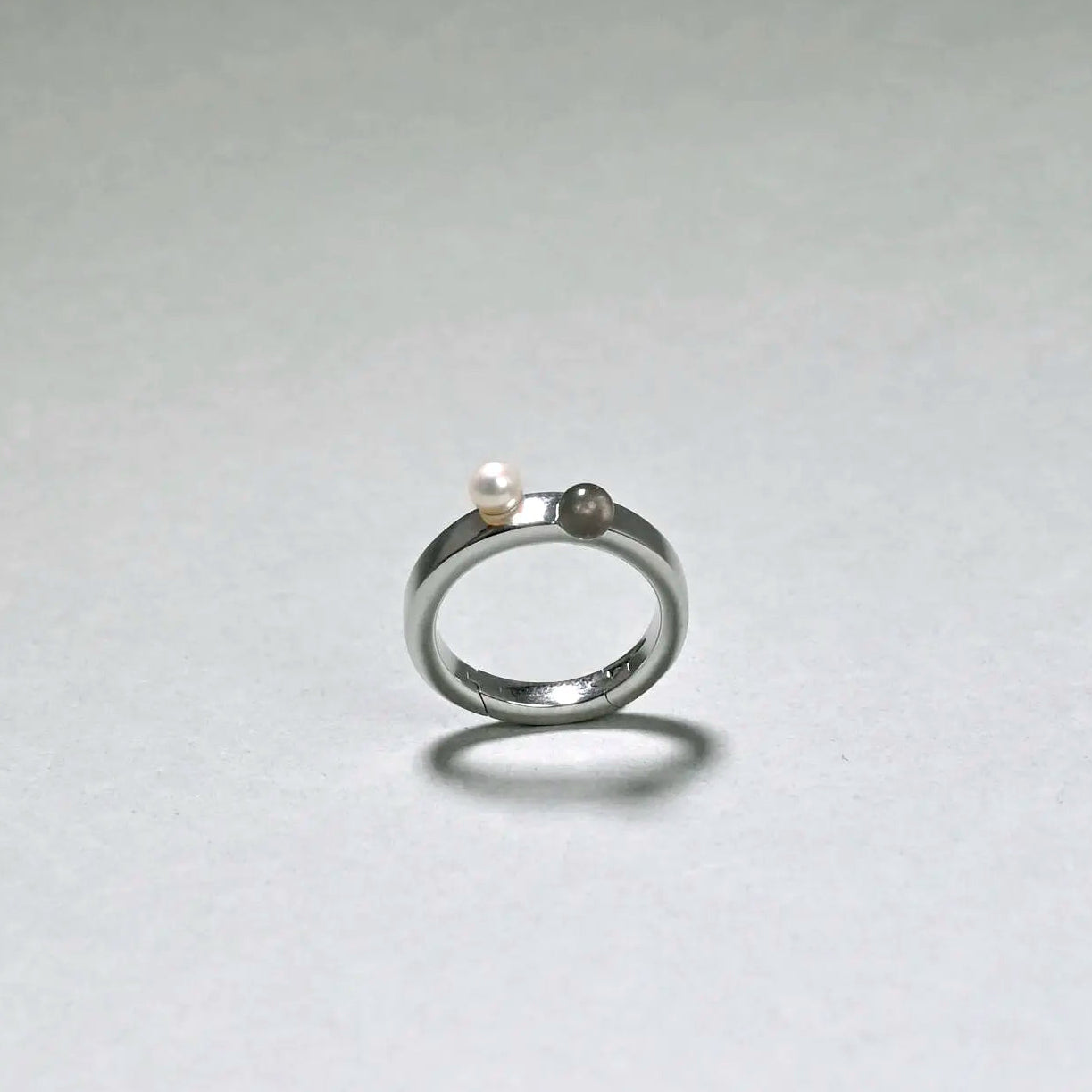 Silver ring with a pearl on a light gray background