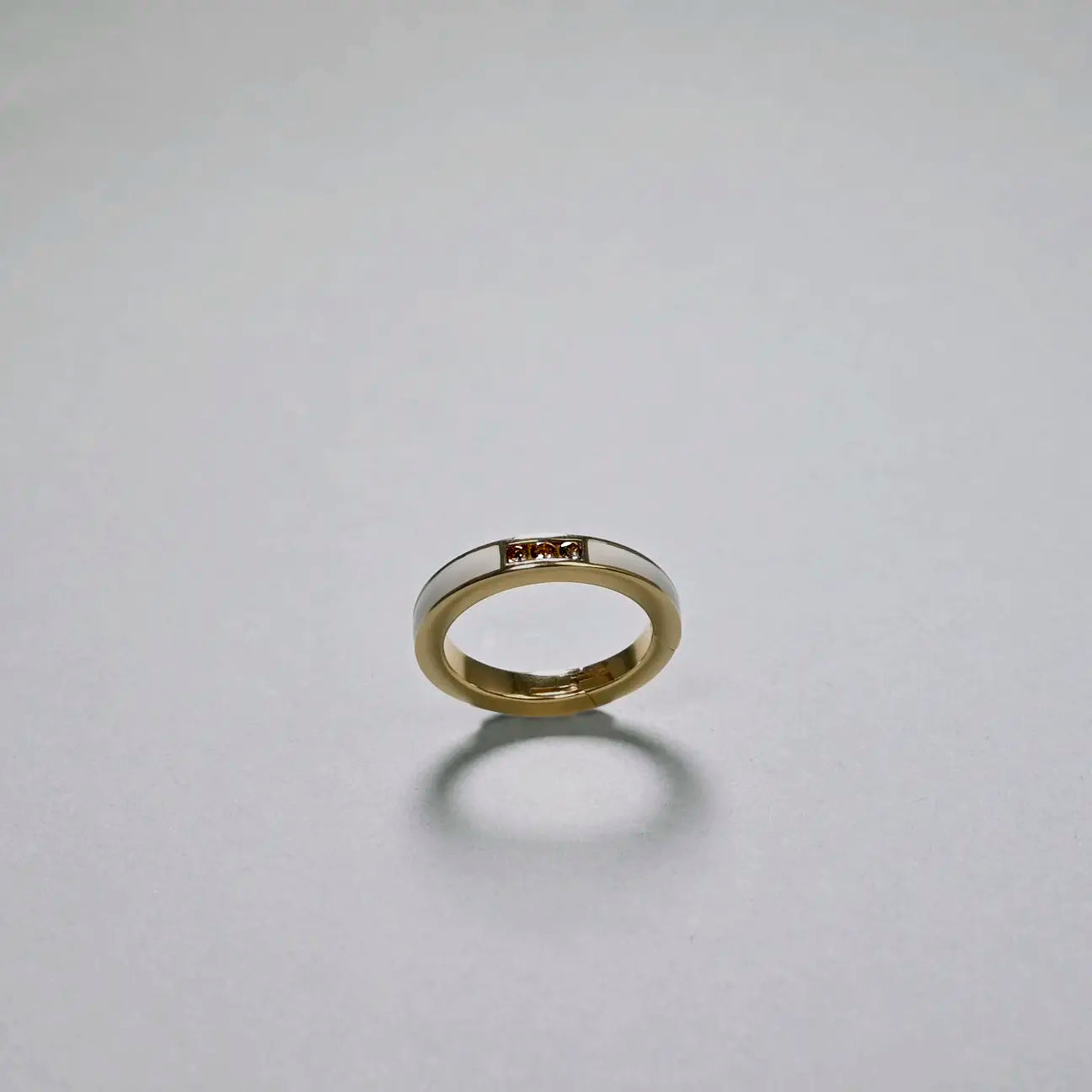 Gold ring with a small gemstone on a light gray background