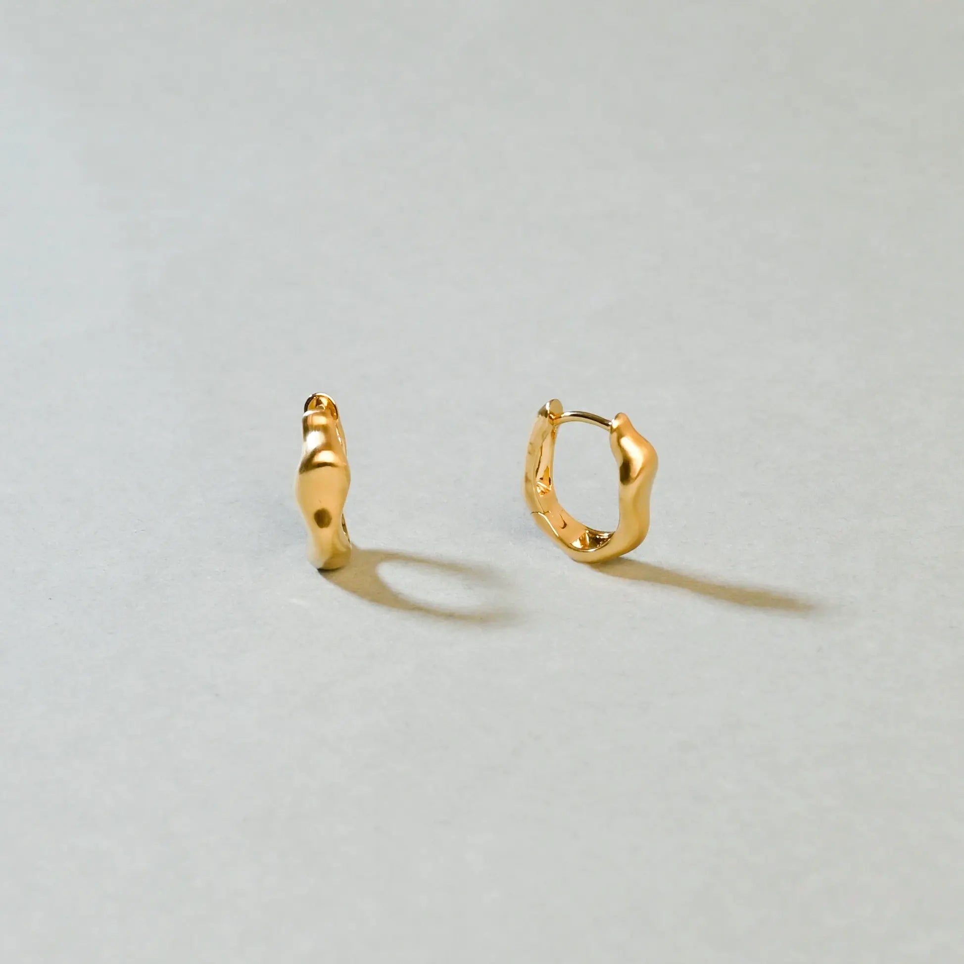 Gold hoop earrings on a light gray background