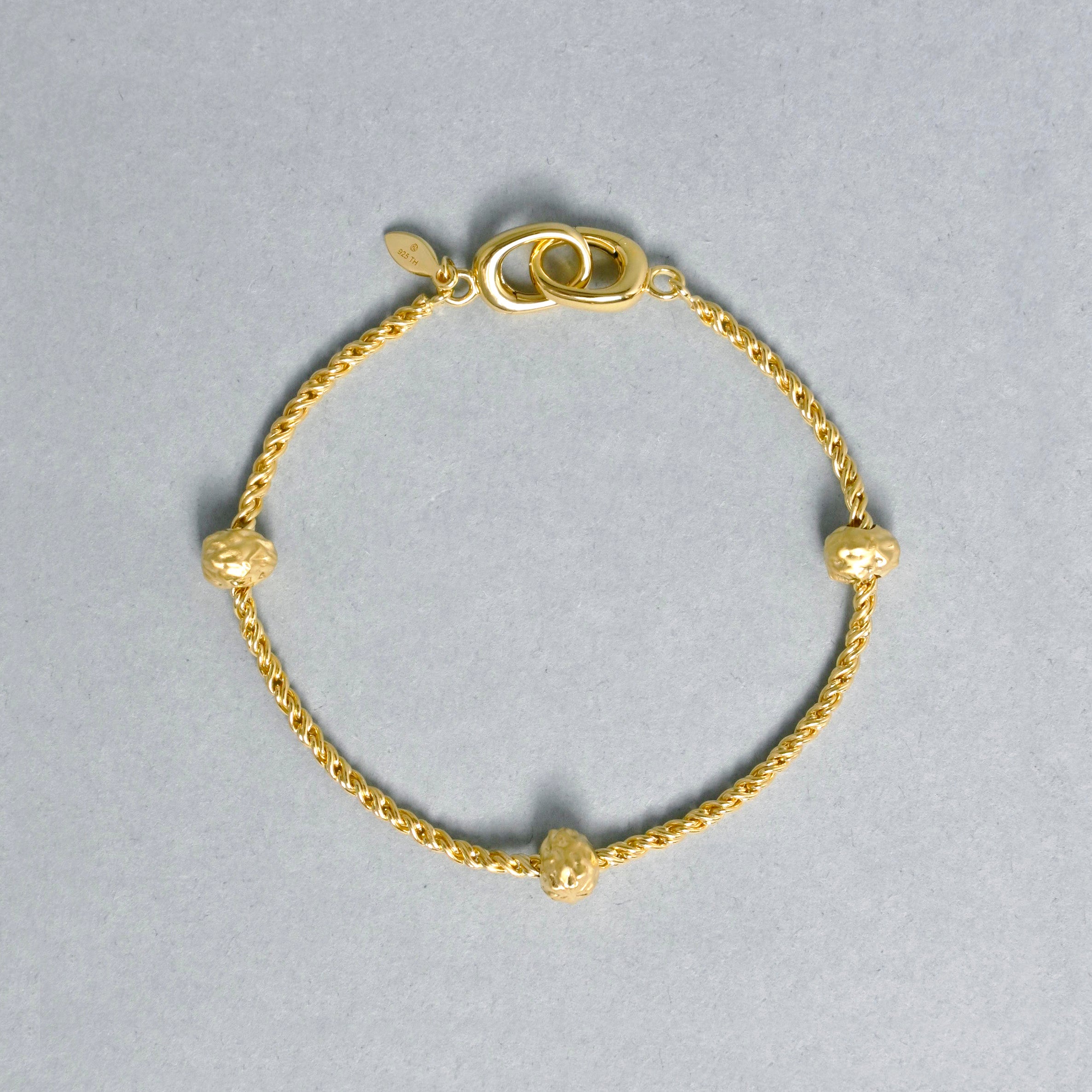 Gold bracelet with small beads on a gray background