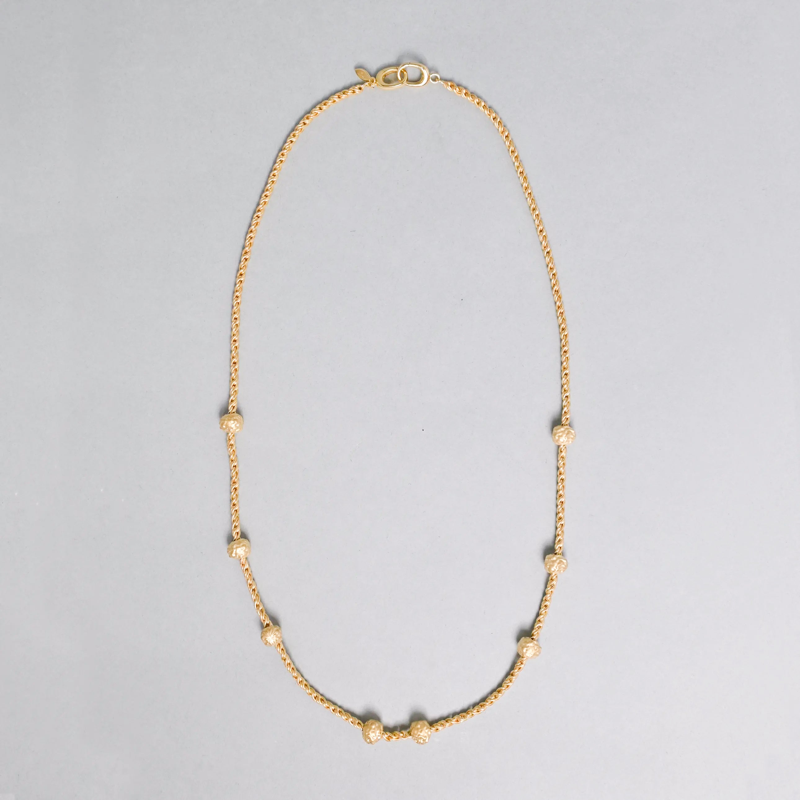 Gold necklace with small beads on a gray background