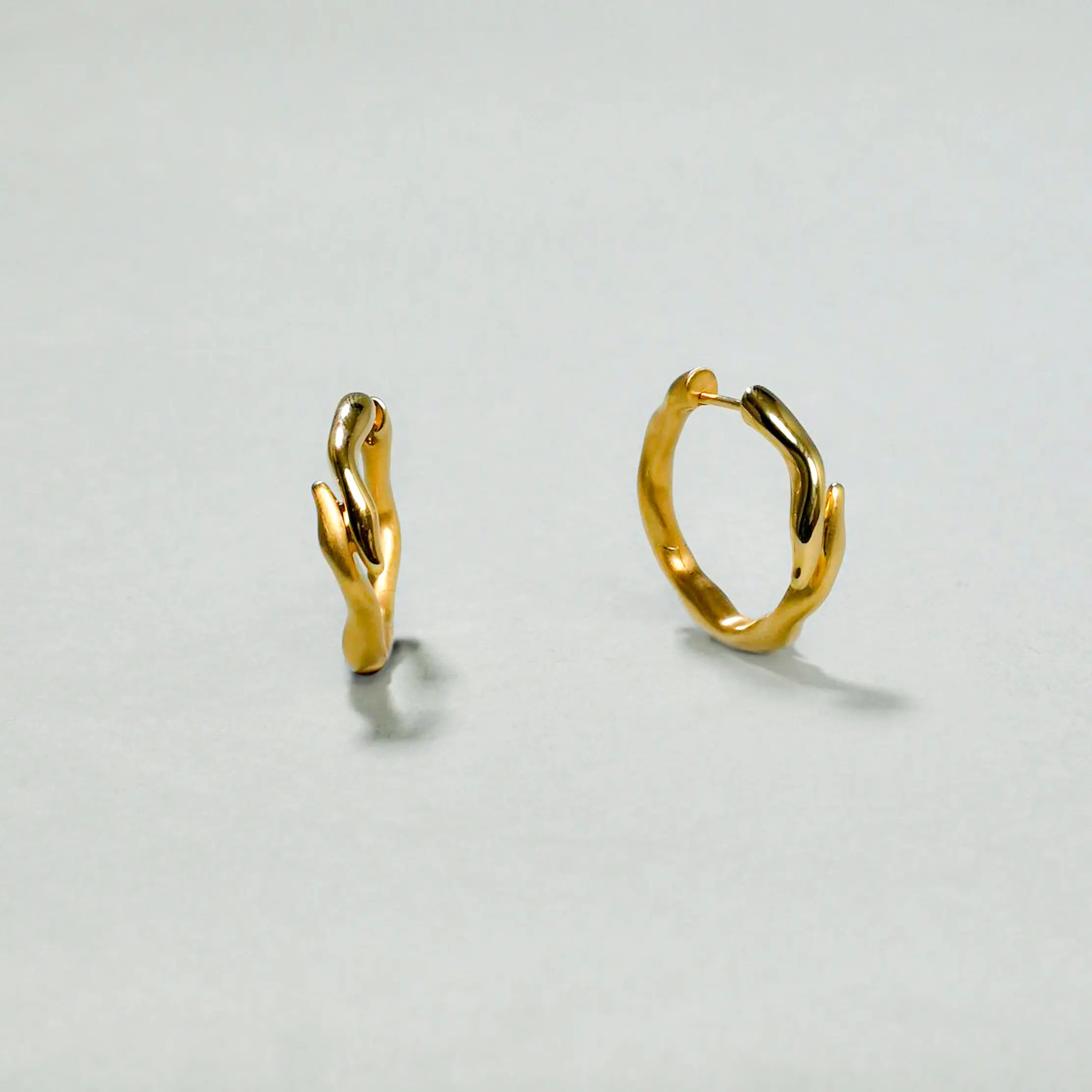 Gold hoop earrings on a light gray background