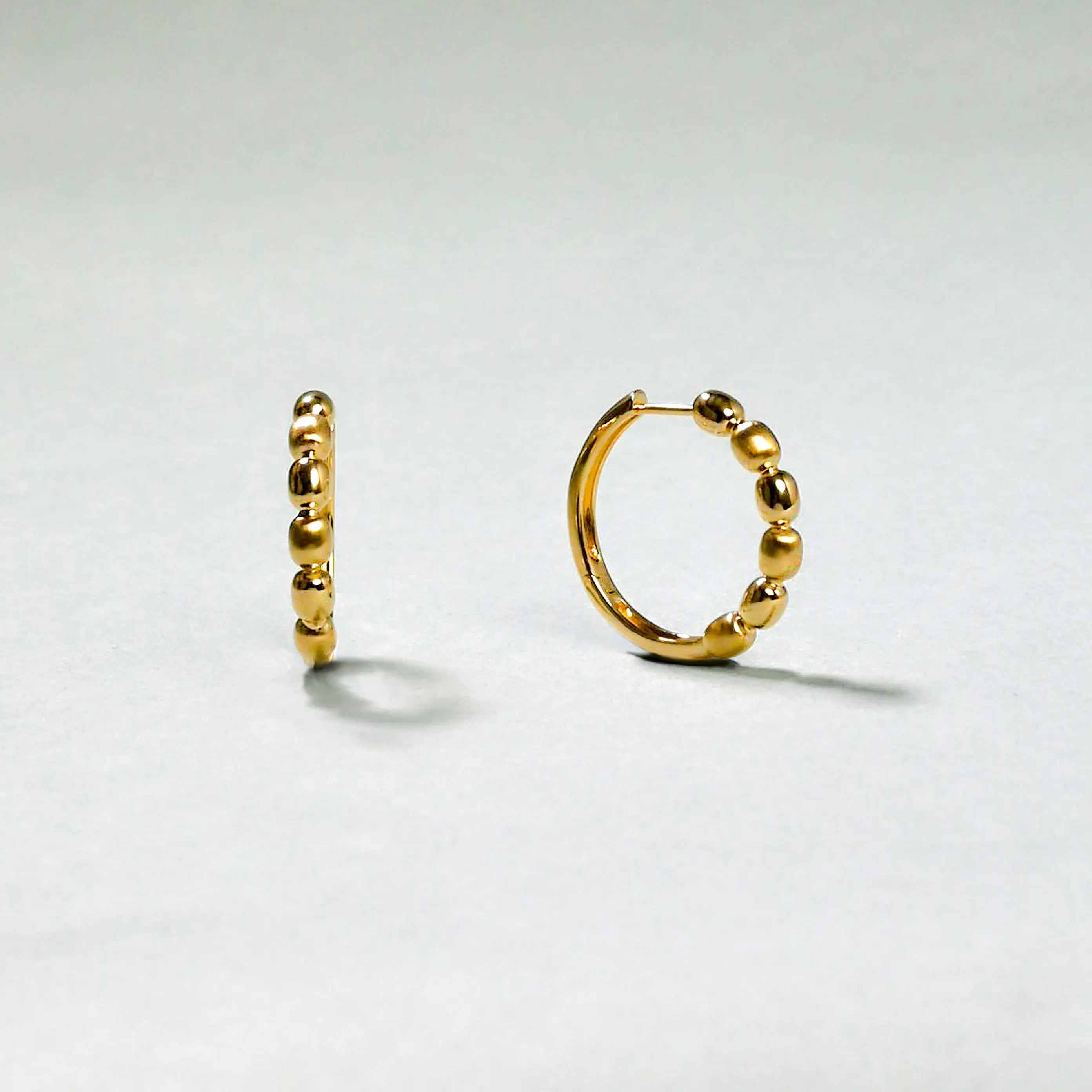 Gold hoop earrings on a light gray background